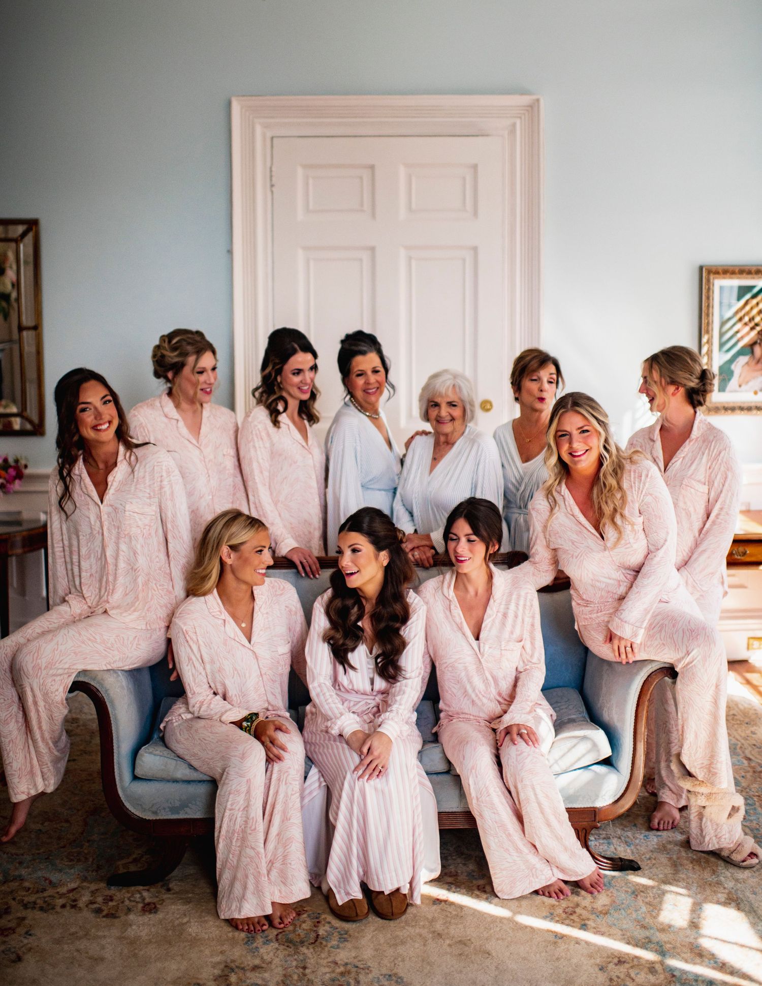 A group in matching white robes sits together on the floor in a casual setting.