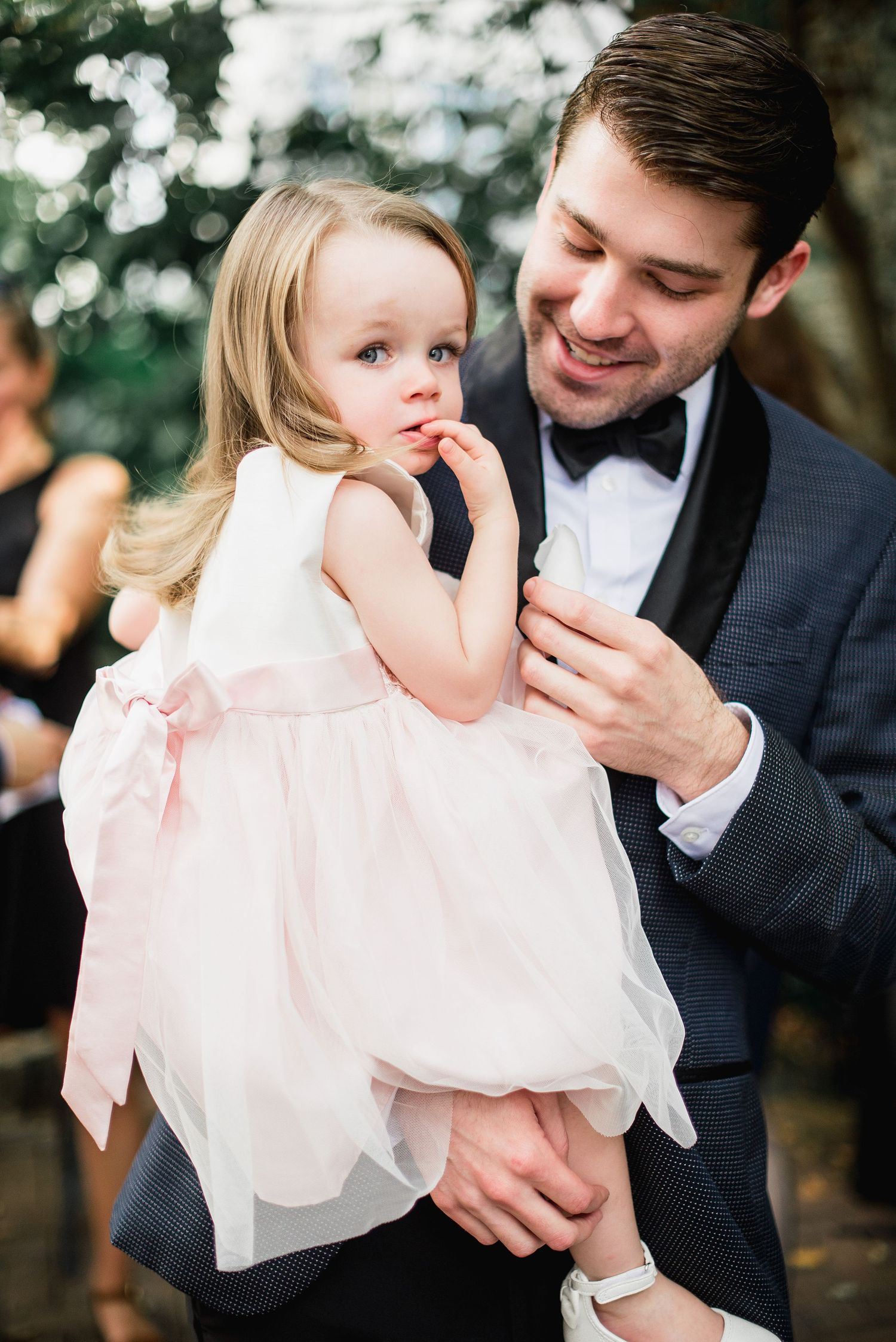 A tender moment between a parent and child in formal attire captured in a series of intimate outdoor portraits.