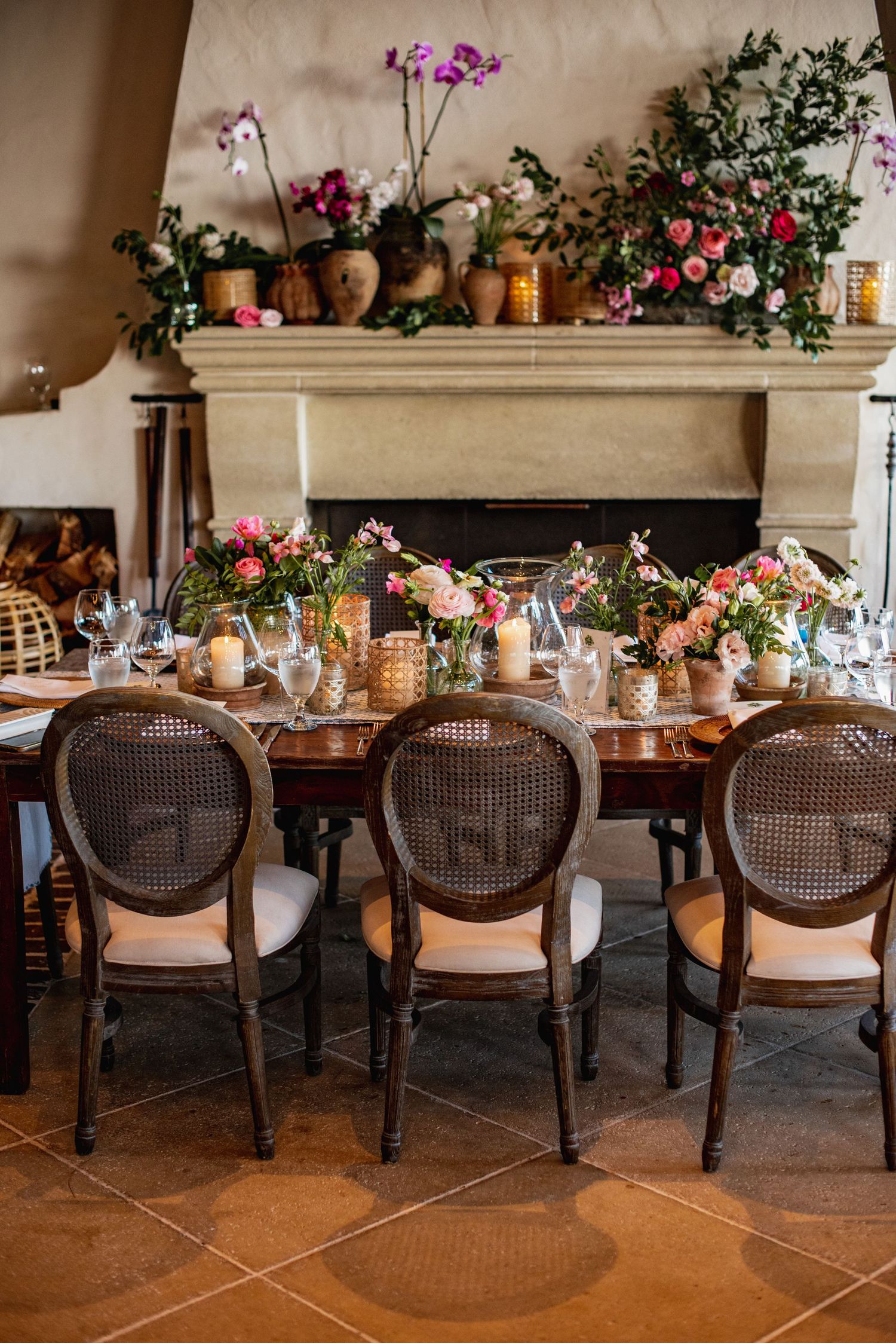 Elegant dining room setup with cane back chairs and floral decorations along a rustic wooden table.