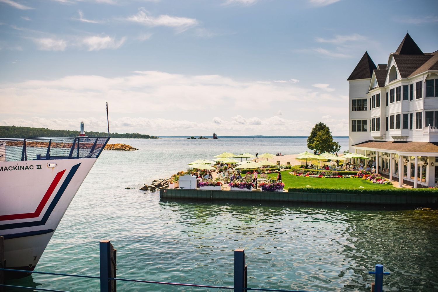 Waterfront hotel with outdoor dining area and docked boats along a peaceful harbor.