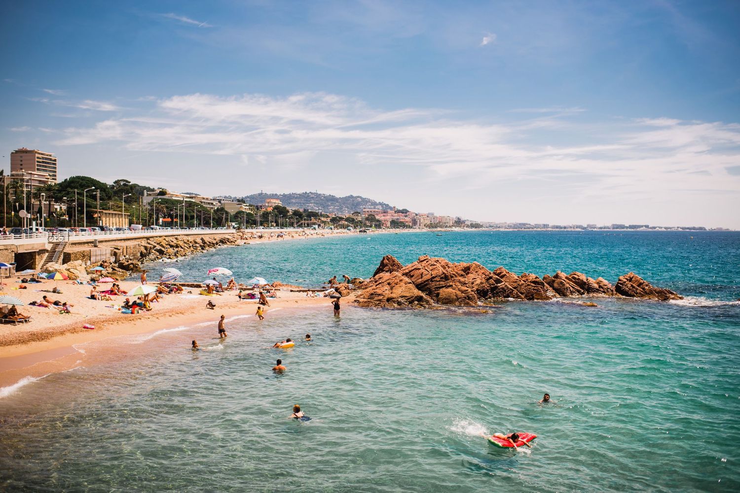 Beautiful Mediterranean beach cove with swimmers enjoying crystal clear turquoise waters.