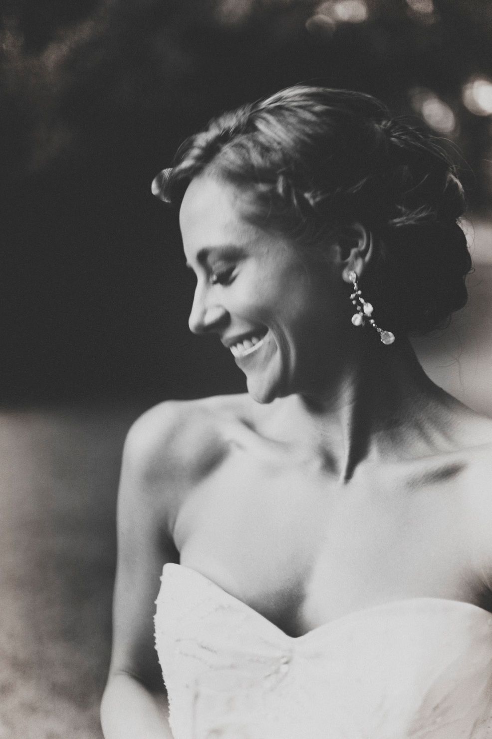 Black and white artistic bridal portrait showing elegant updo hairstyle and strapless dress detail.