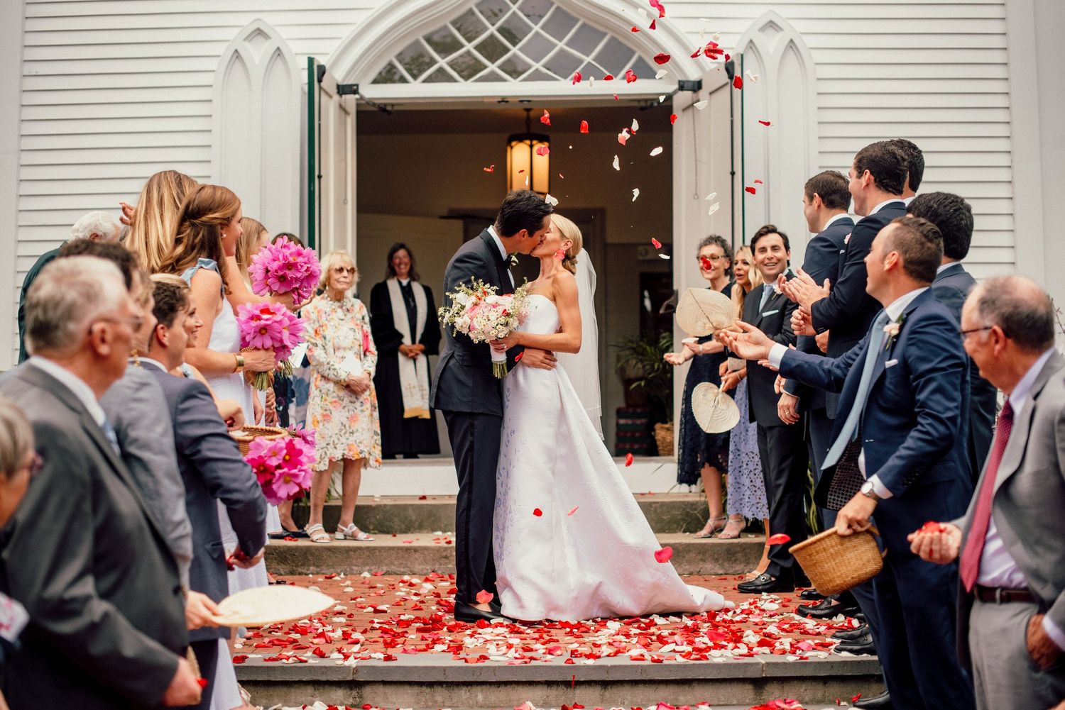 Wedding ceremony exit with rose petals being thrown as couple leaves church entrance.