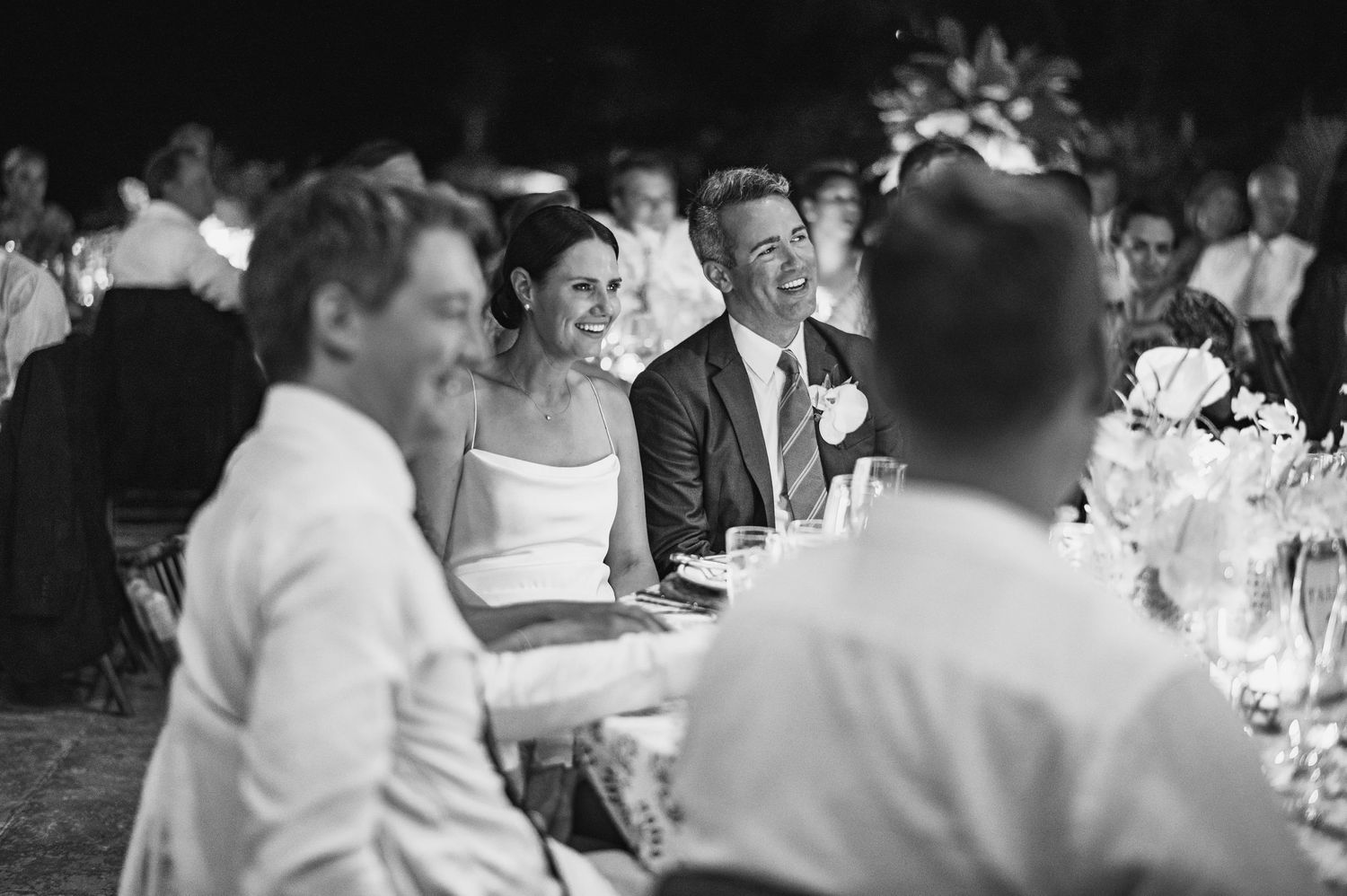 Wedding guests smile and laugh during an elegant black and white reception dinner.