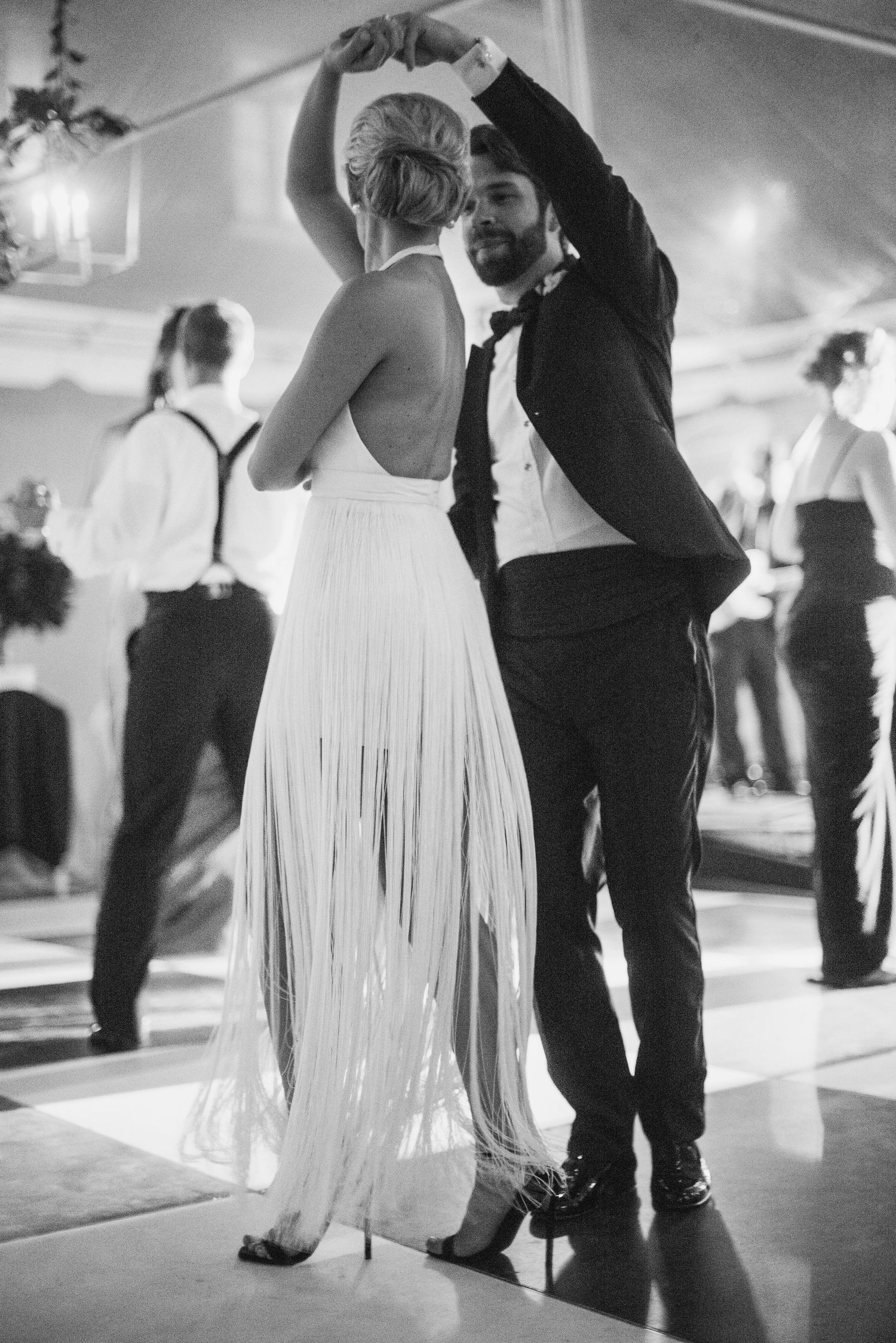 Black and white photo sequence of dancers in flowing white dresses and dark suits moving across a dance floor.