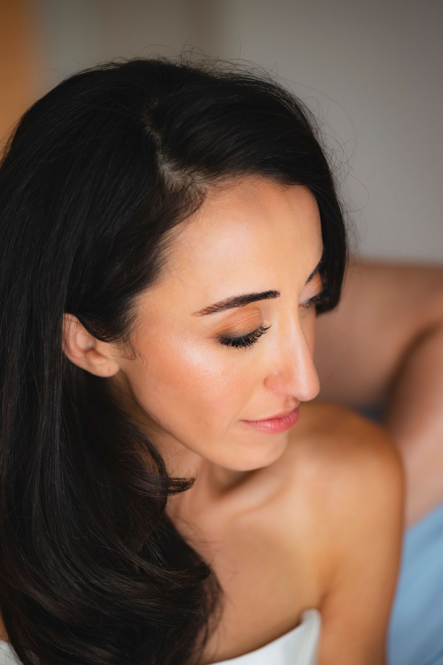 Close up beauty portrait showing dark hair and pink lipstick against soft blurred background.