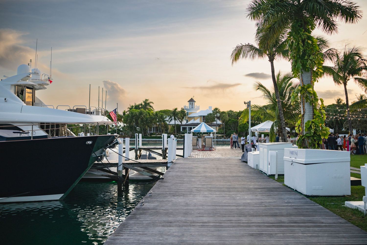 Luxury marina dock with palm trees and boats at sunset creating a serene waterfront atmosphere.