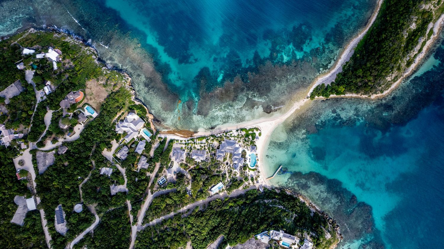 Bird's eye view of a coastal development with white buildings and blue waters.