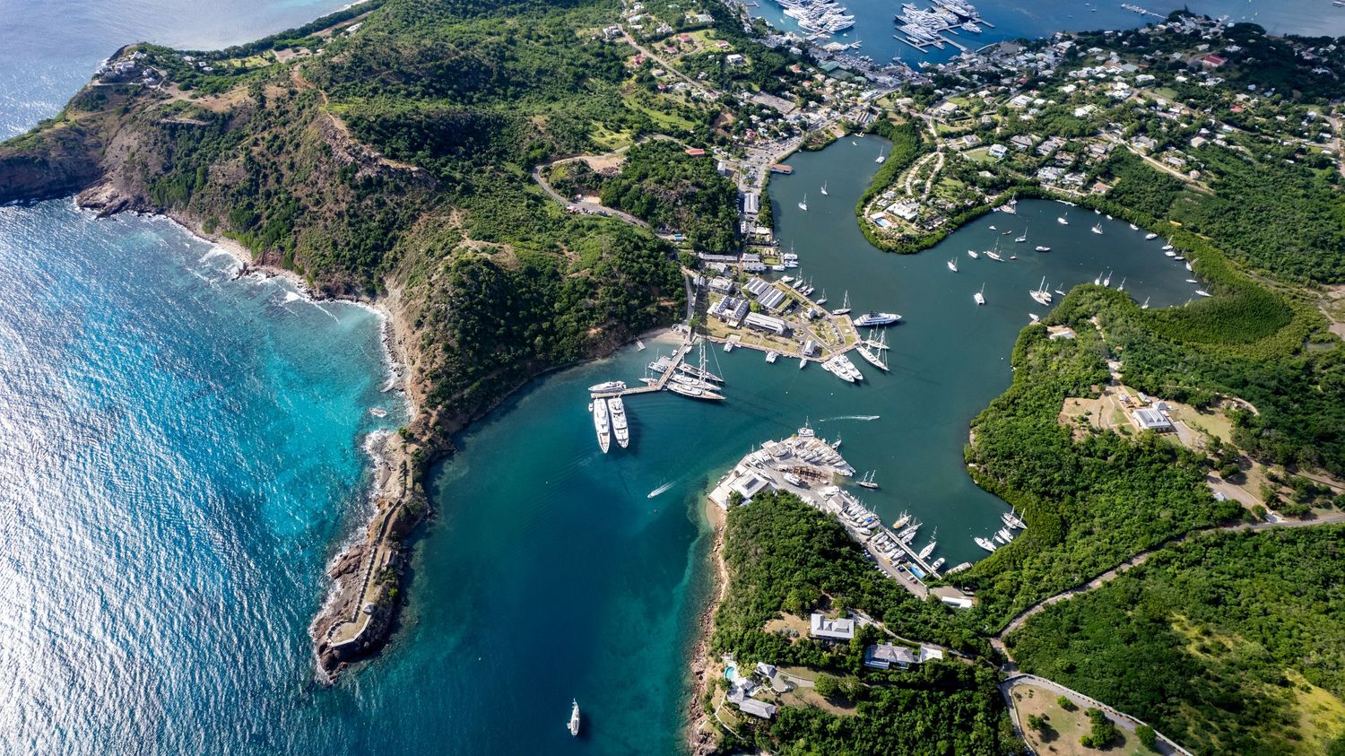 Scenic drone shot of a curved coastline with crystal clear waters and tropical vegetation.