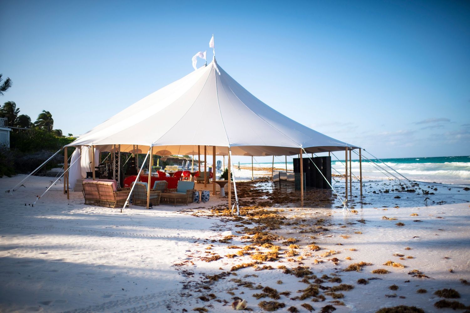 White beach tent structures set up along a tropical shoreline with crystal clear blue waters.