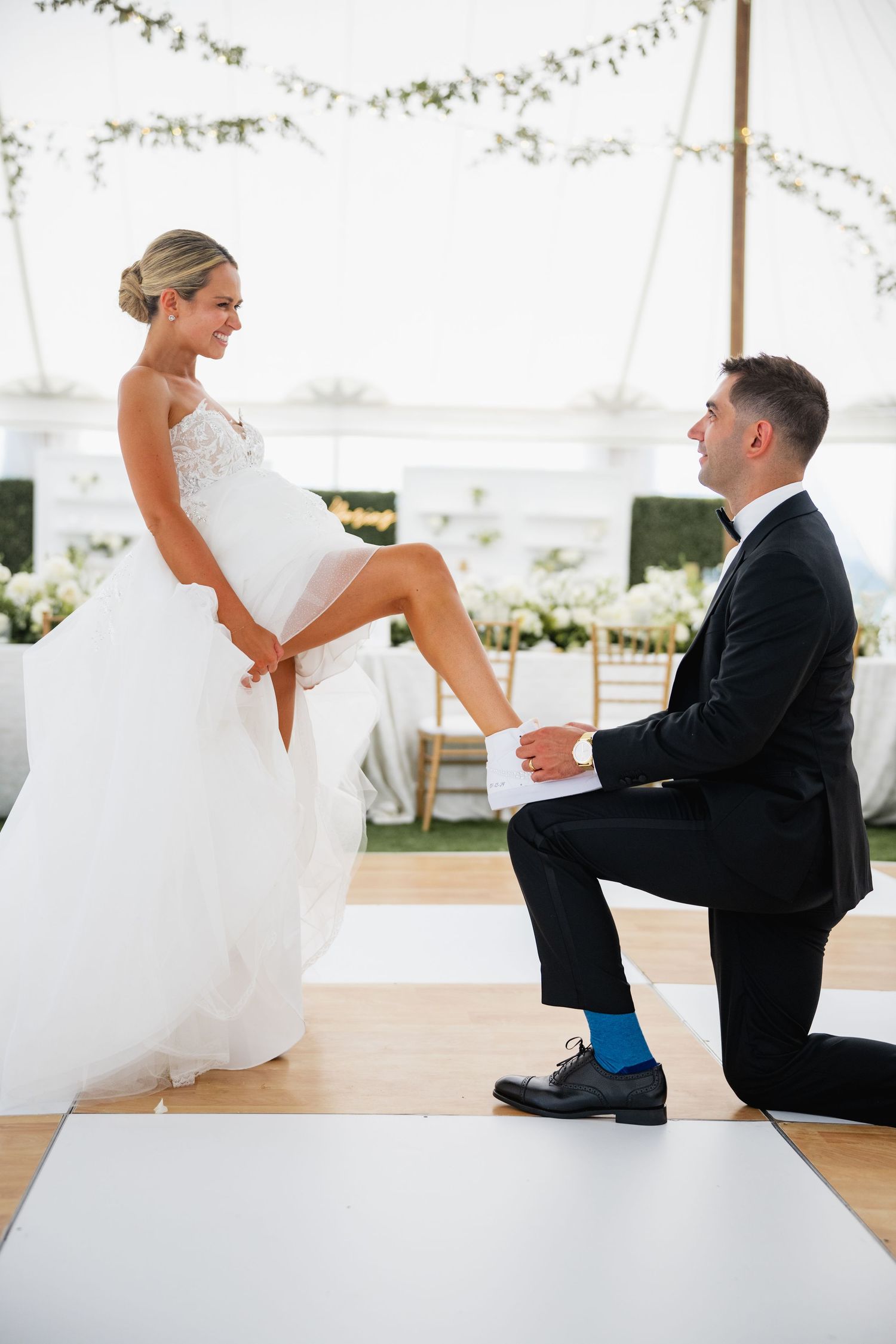 Playful wedding dance sequence on a white dance floor under an outdoor tent.