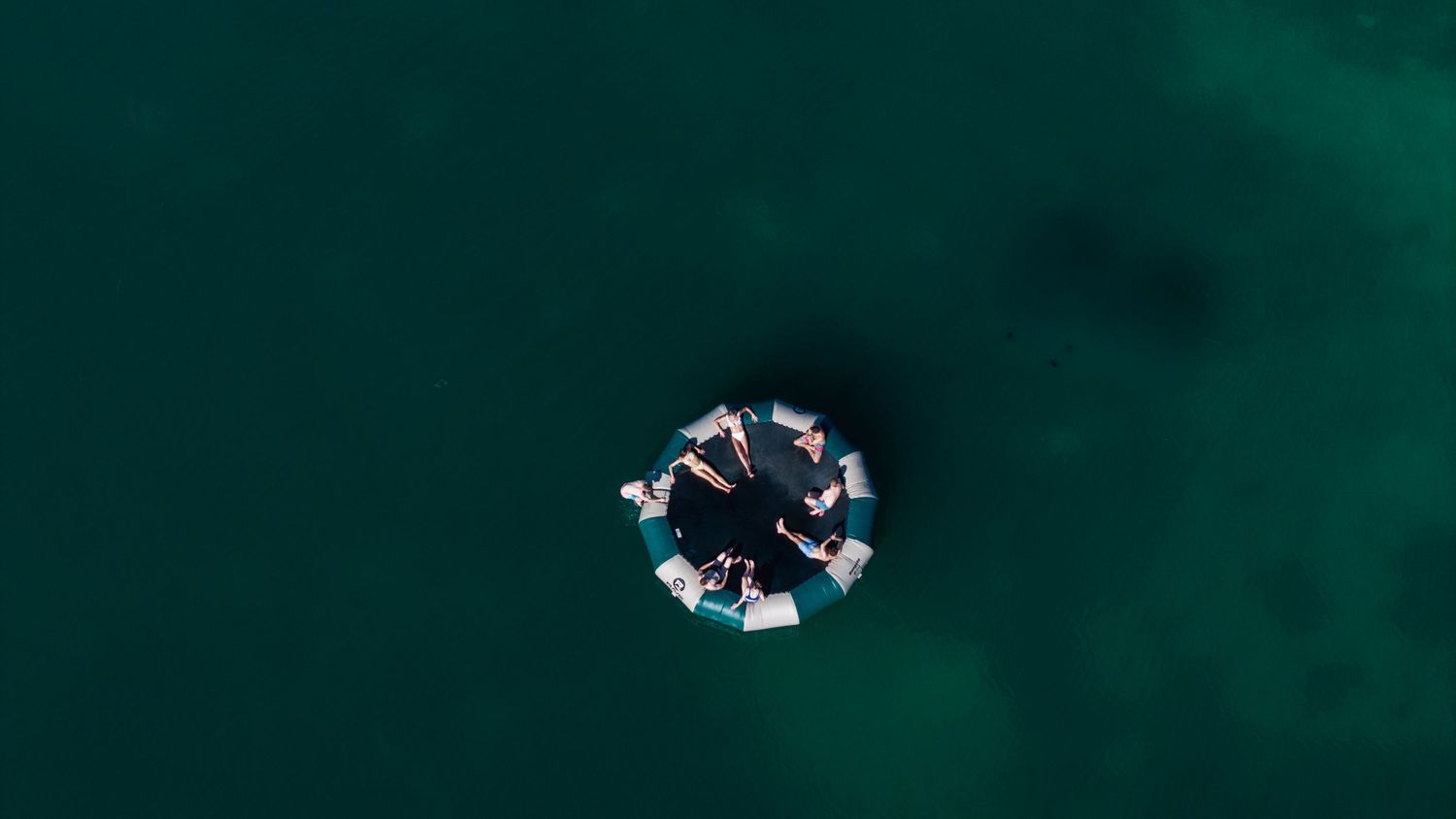 Aerial view of people floating in a circle formation on green ocean water.