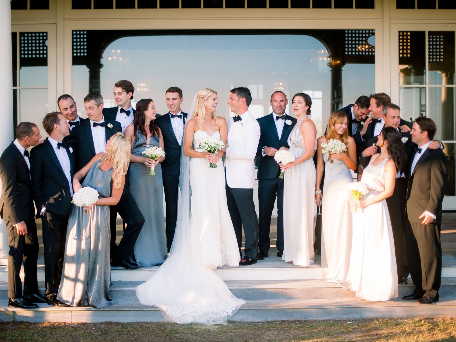 A wedding party stands in a line during an outdoor reception ceremony at sunset.