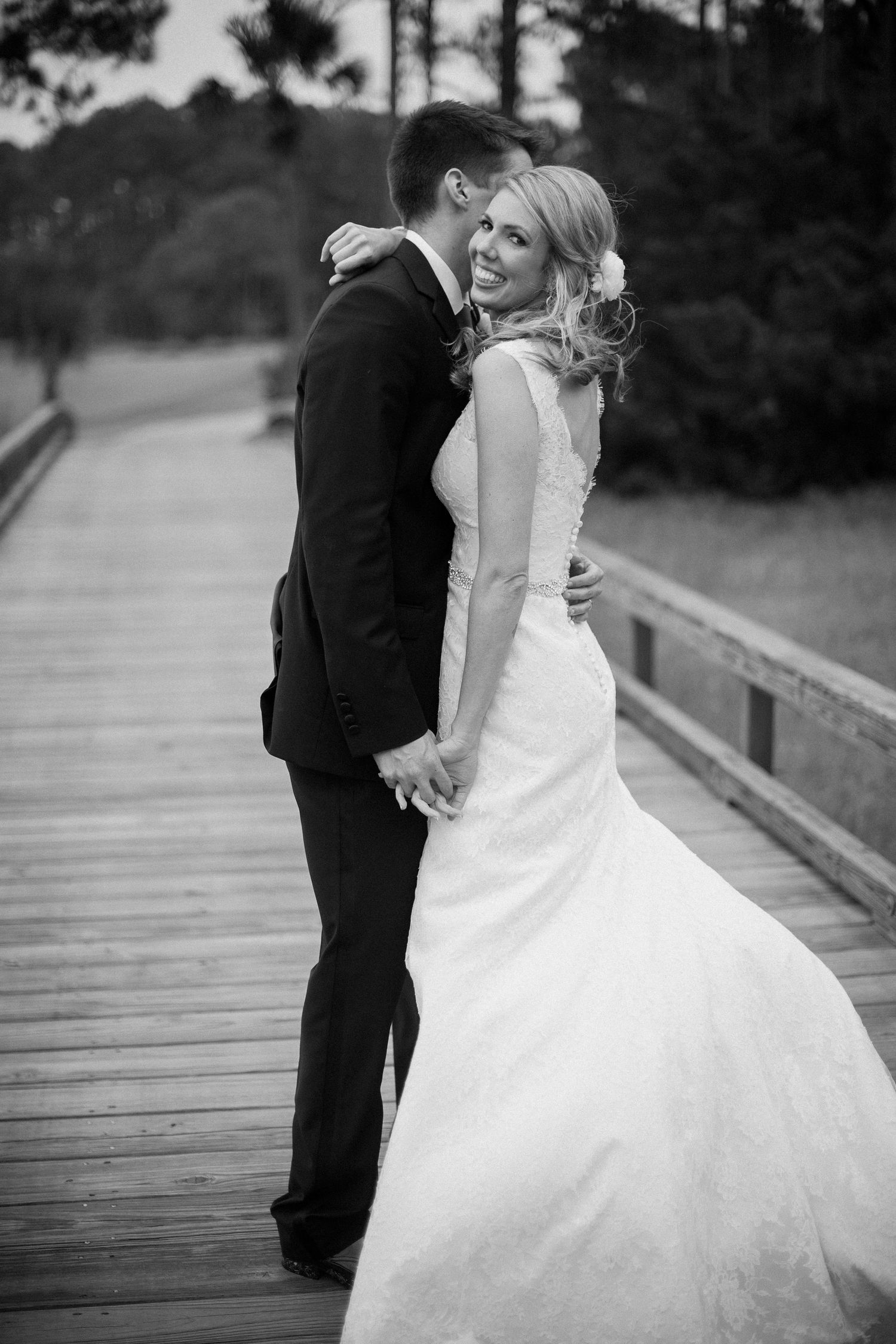 Black and white wedding photos of a couple sharing intimate moments on a wooden boardwalk.