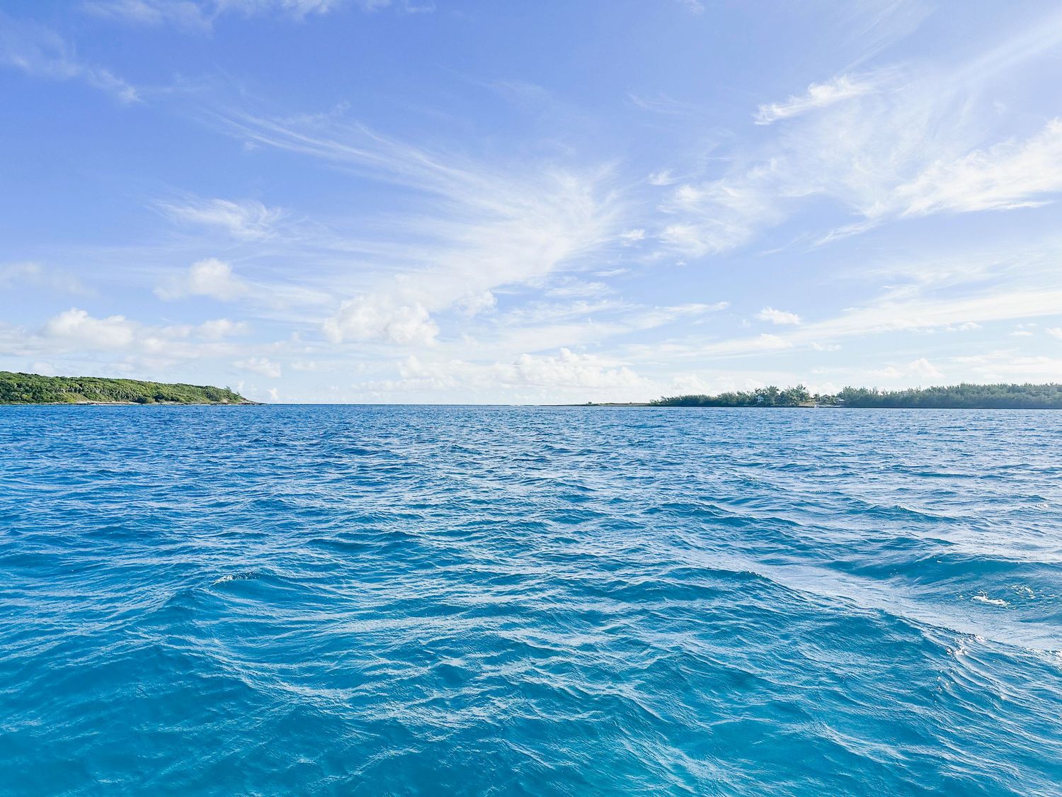 Crystal clear turquoise ocean waters stretch to the horizon under bright blue skies.