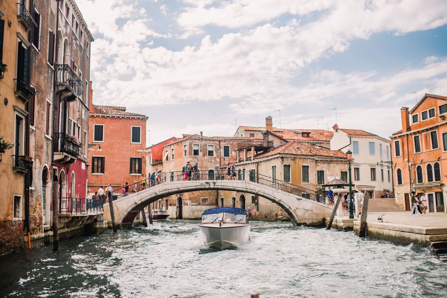 Panoramic view of colorful buildings and bridges along Venice's scenic canals under a cloudy sky.