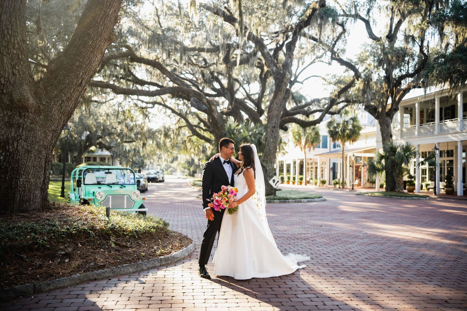 Romantic wedding photo session on a tree-lined brick pathway with Spanish moss hanging overhead.