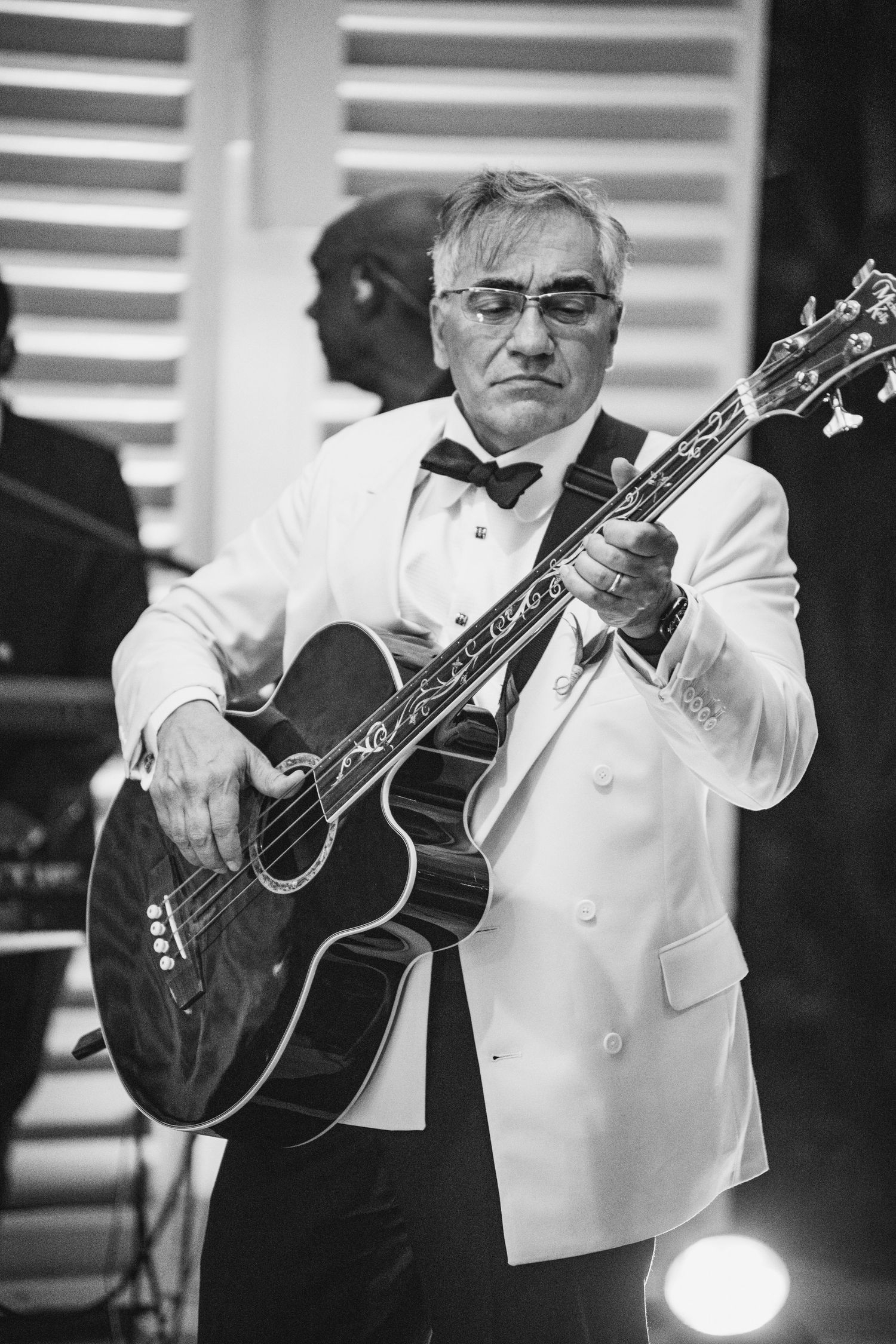 Black and white photo sequence shows a musician playing an acoustic guitar while wearing a white formal jacket.