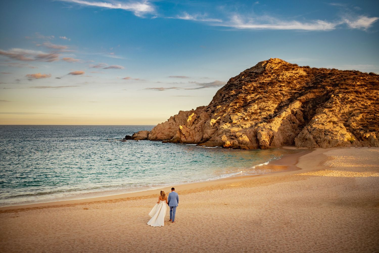 A panoramic sequence of coastal wedding photos showing a beach and cliffs against a vibrant blue sky at sunset.