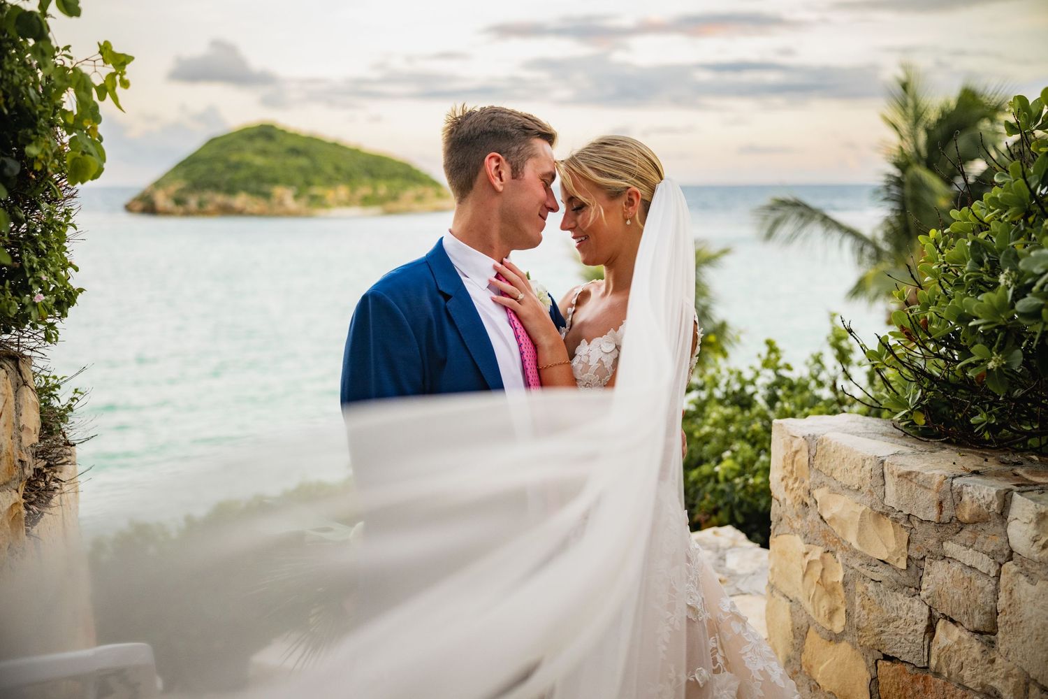 Romantic waterfront wedding ceremony with ocean and palm trees in the background.