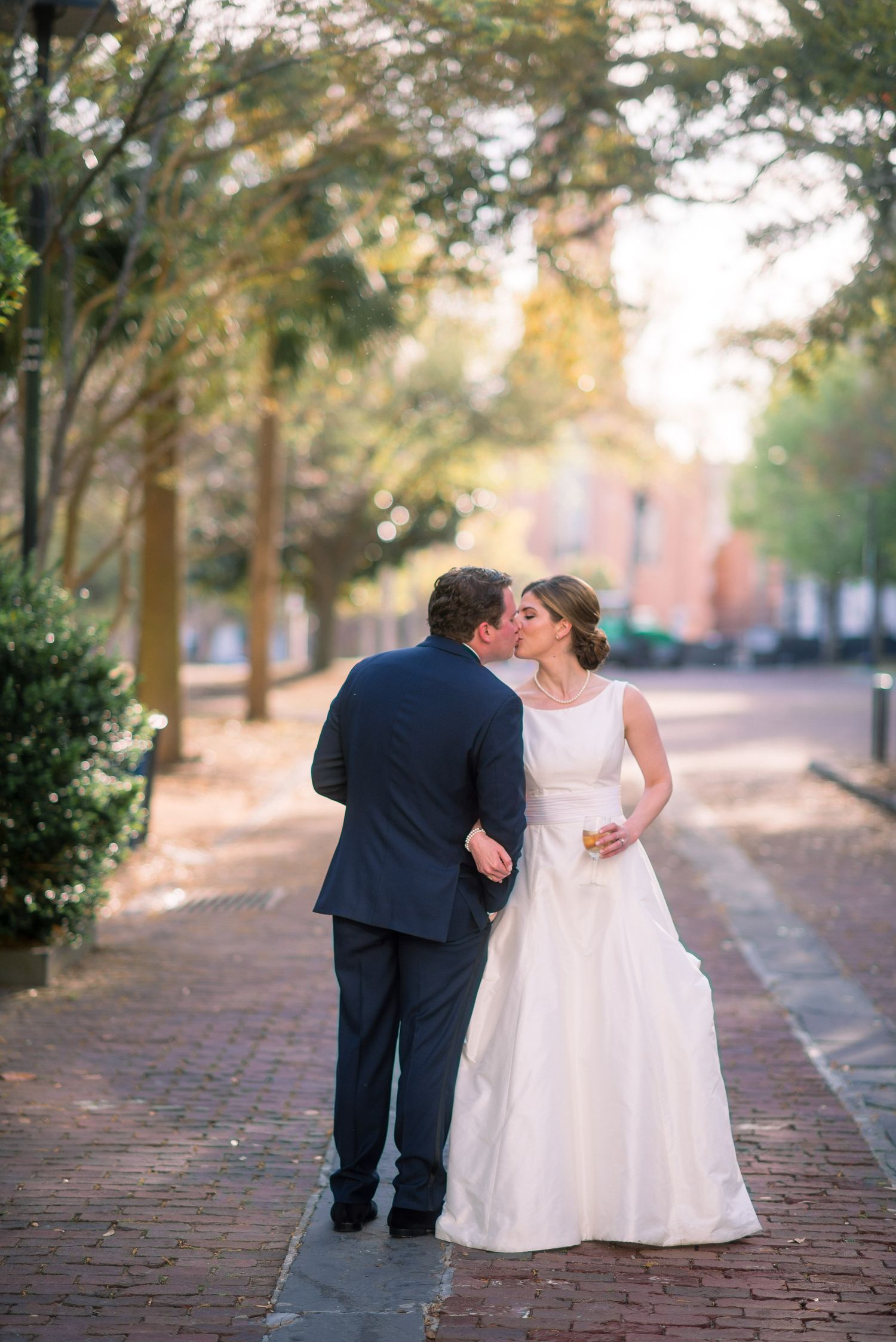 A romantic wedding couple shares tender moments on a brick pathway lined with trees during their photo session.
