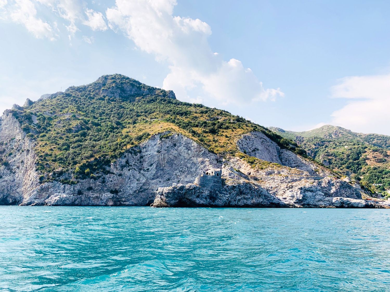 Coastal mountain landscape with rugged cliffs meeting turquoise Mediterranean waters.