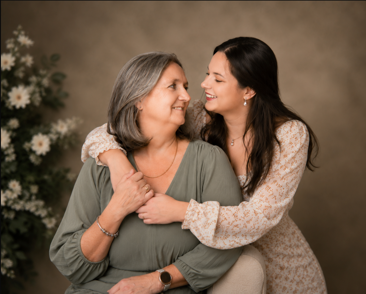 A mother and daughter share a joyful embrace, smiling at each other in a professional studio portrait.