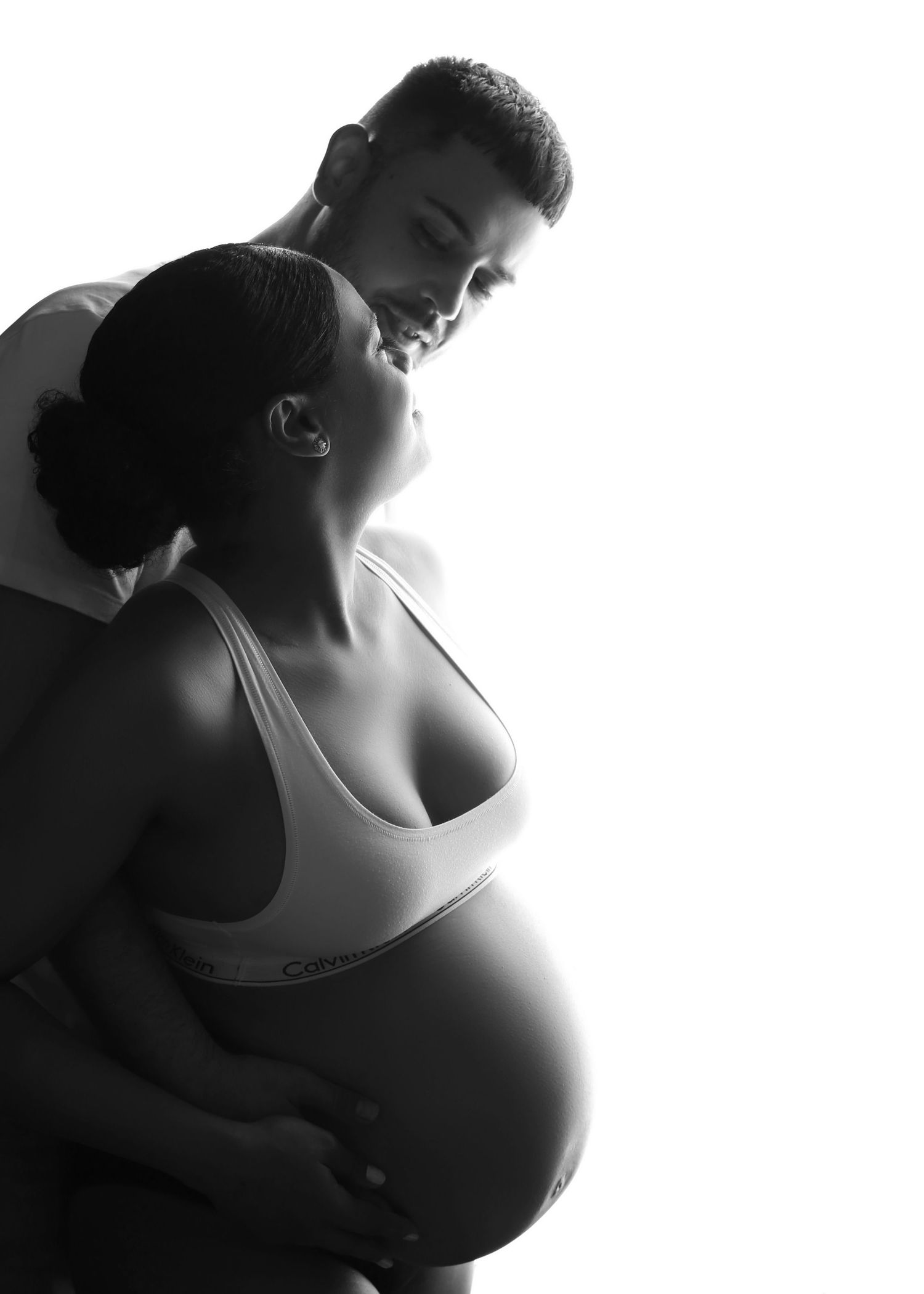 Black and white maternity photo of pregnant couple sharing a tender moment together.