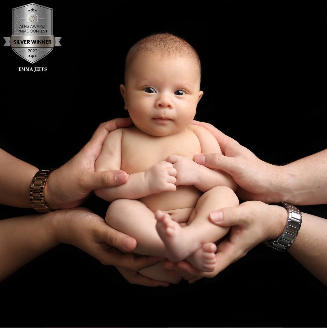 An award winning image showing mum and dad's hands gently cradling baby, a tender symbol of love and protection.