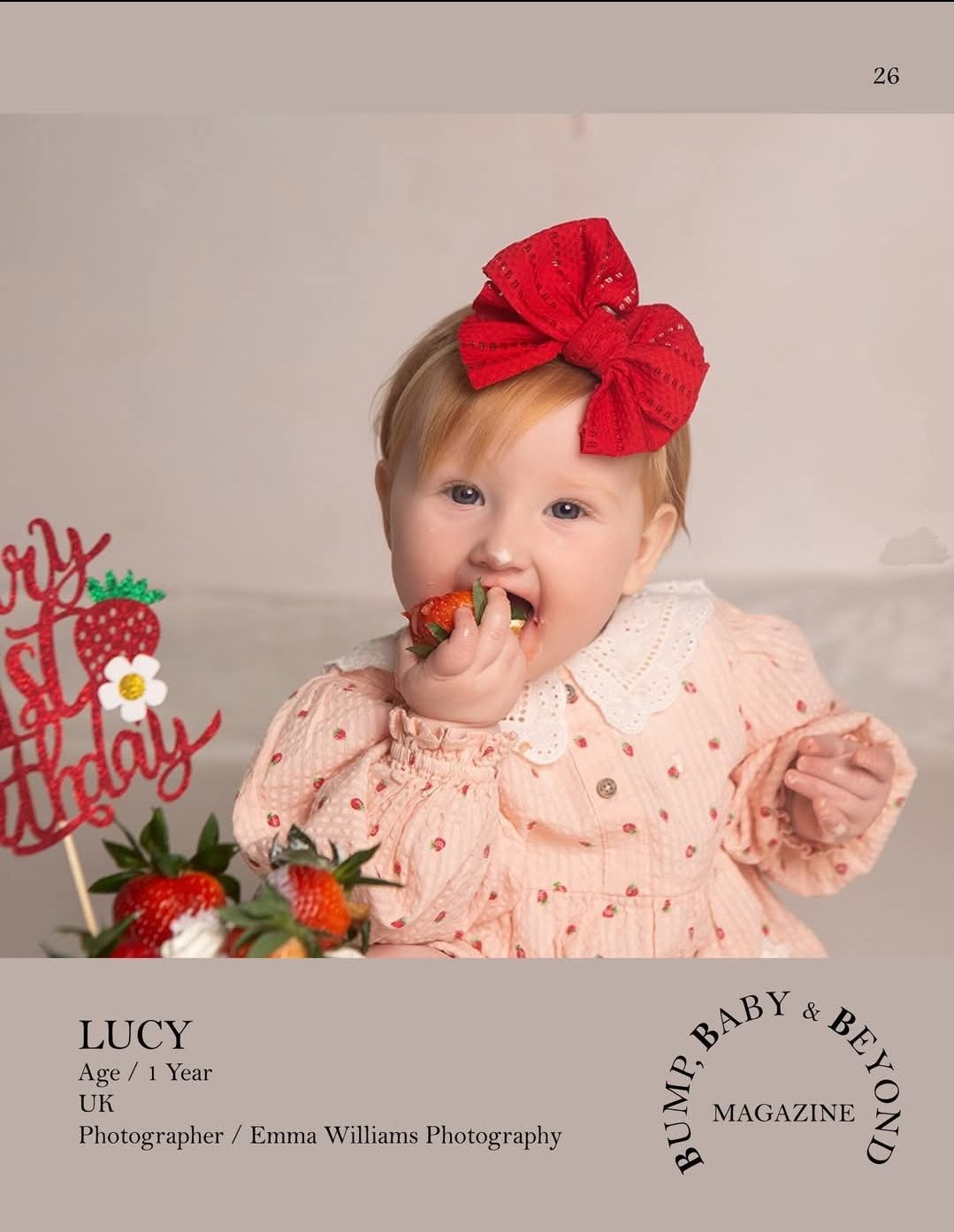 Baby Lucy, age 1, wearing a red bow headband eating a strawberry at her first birthday cake smash session.