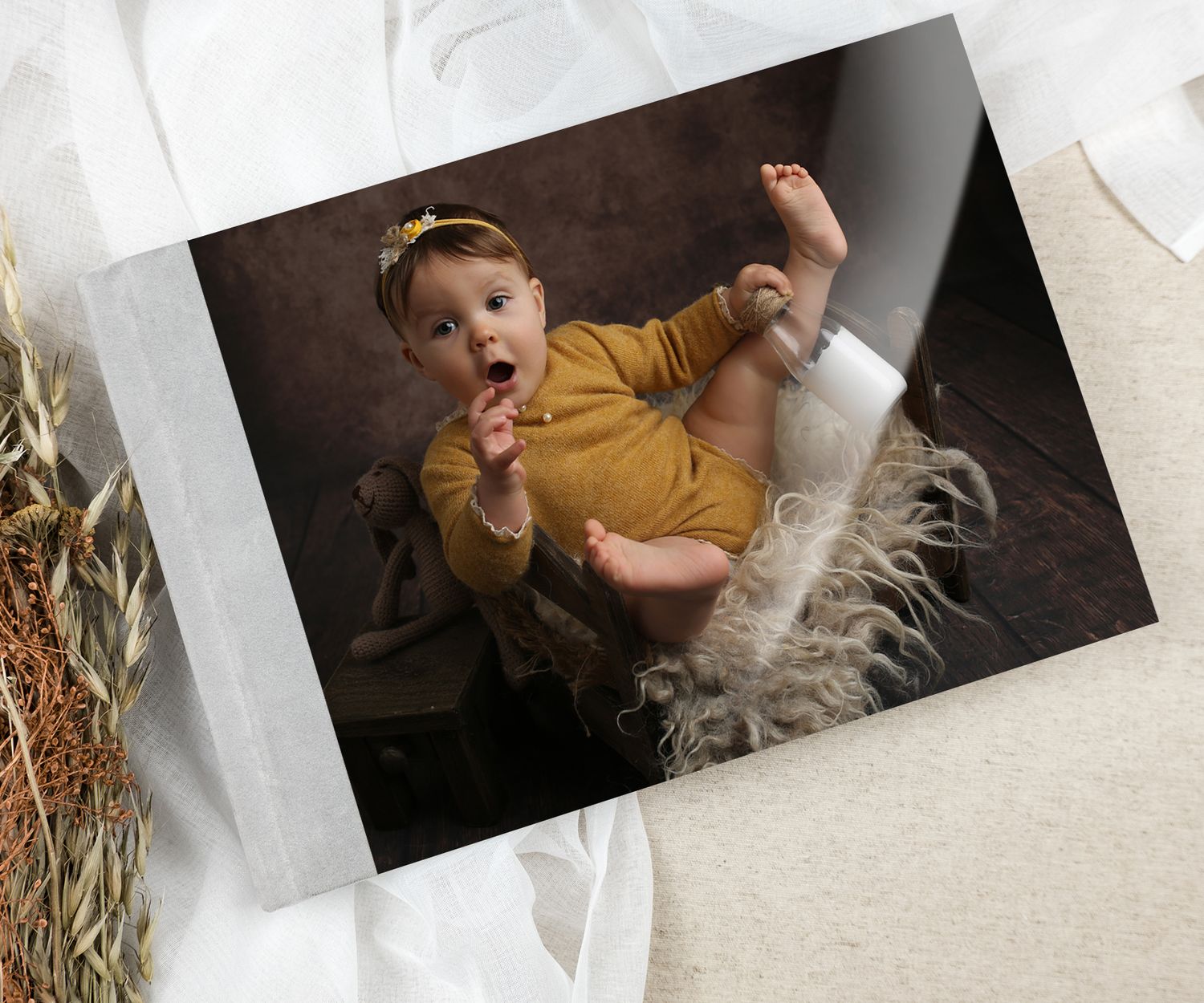 Adorable baby in yellow onesie sitting in a fluffy basket, professional portrait photography on dark background.