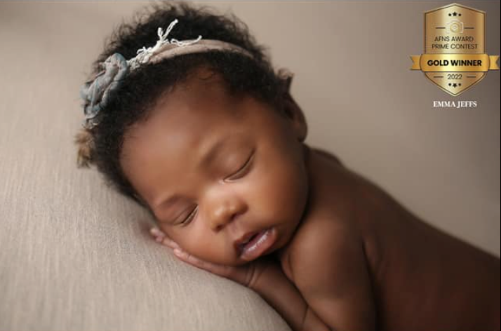An award winning image of baby gently cradled in hands, capturing tenderness, trust and pure innocence.