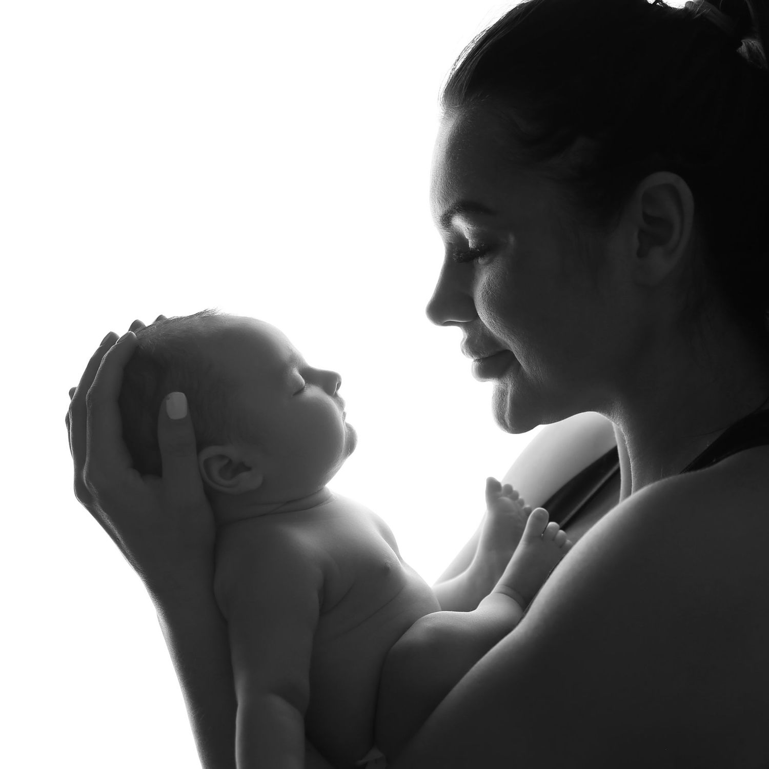 Black and white silhouette of a mother tenderly holding her newborn baby, captured in a beautiful maternity portrait.