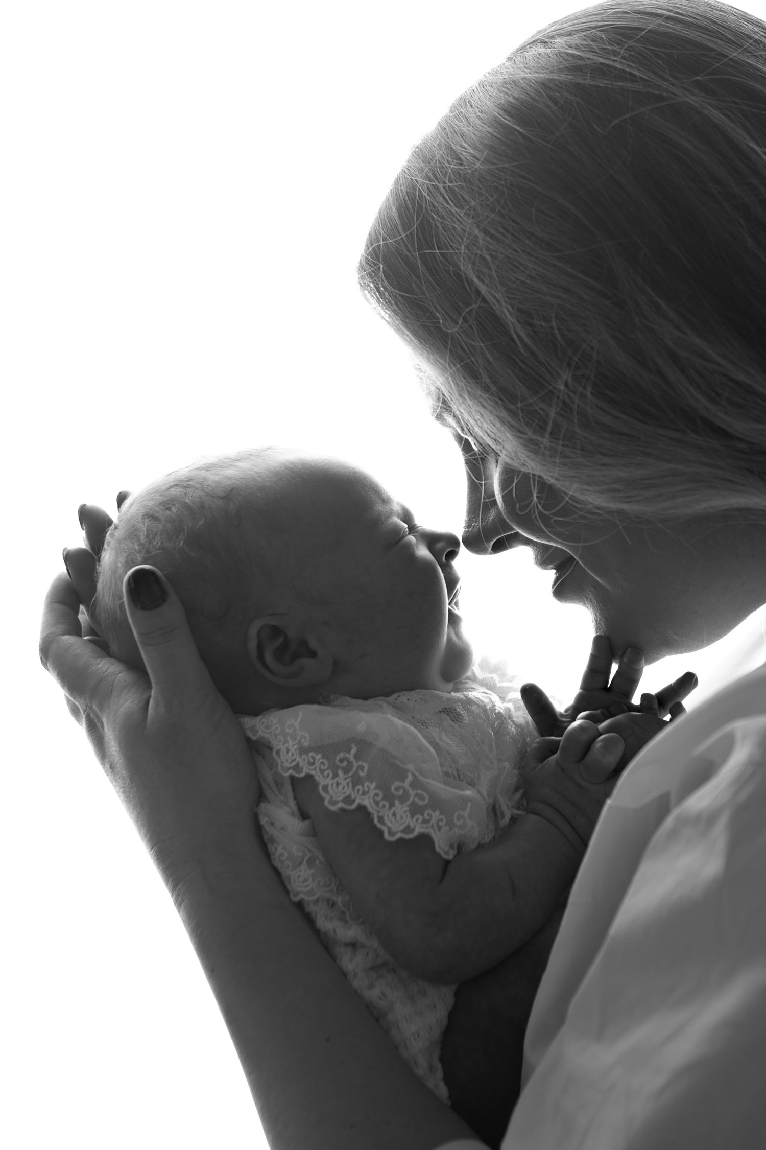 Black and white silhouette of a mother tenderly holding her newborn baby close to her face.