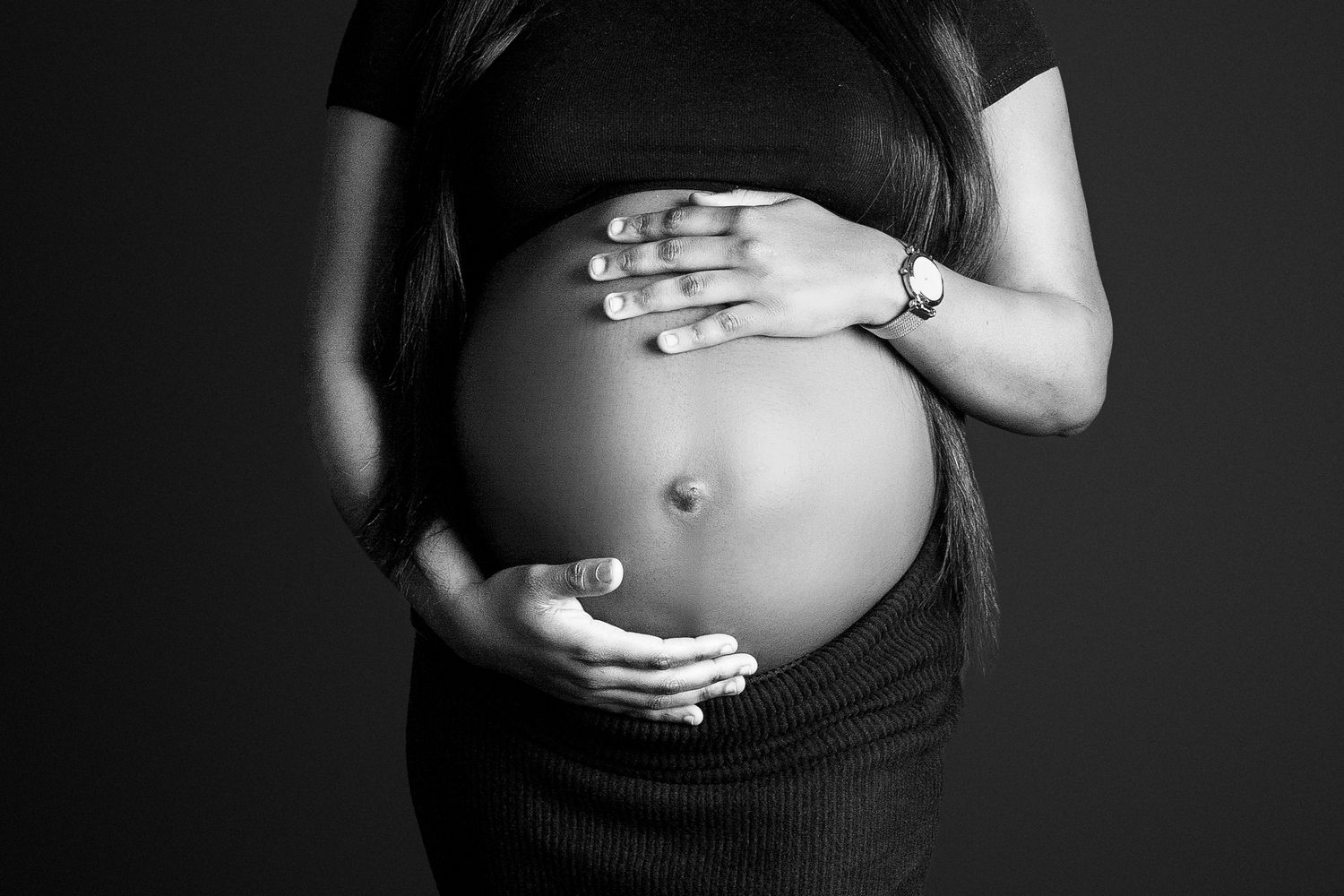 Parents' hands gently placed around the bump in a yin yang style, symbolising balance, love and connection.