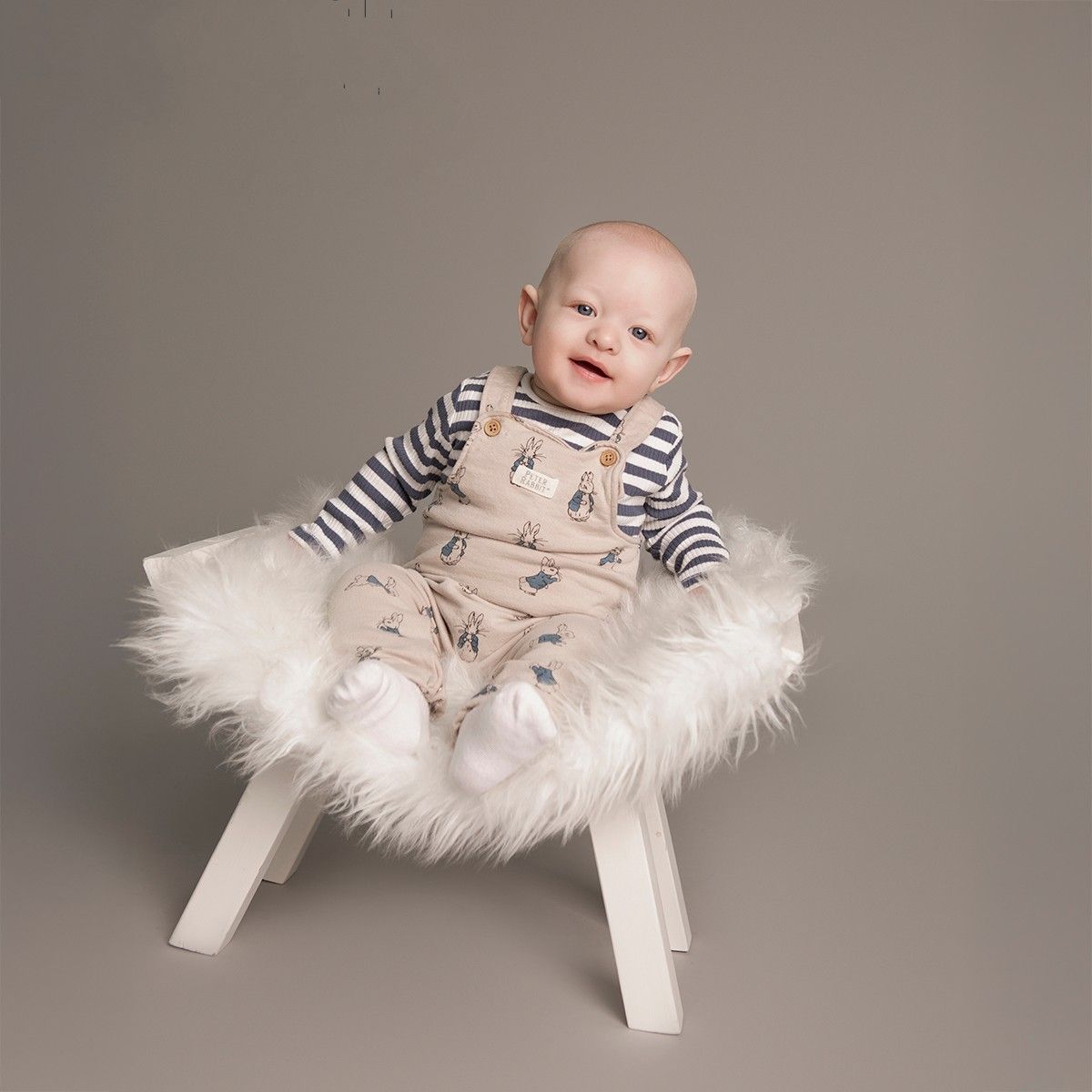 A cosy portrait of a 7 month old posed on soft fur, creating a warm and gentle textured backdrop.