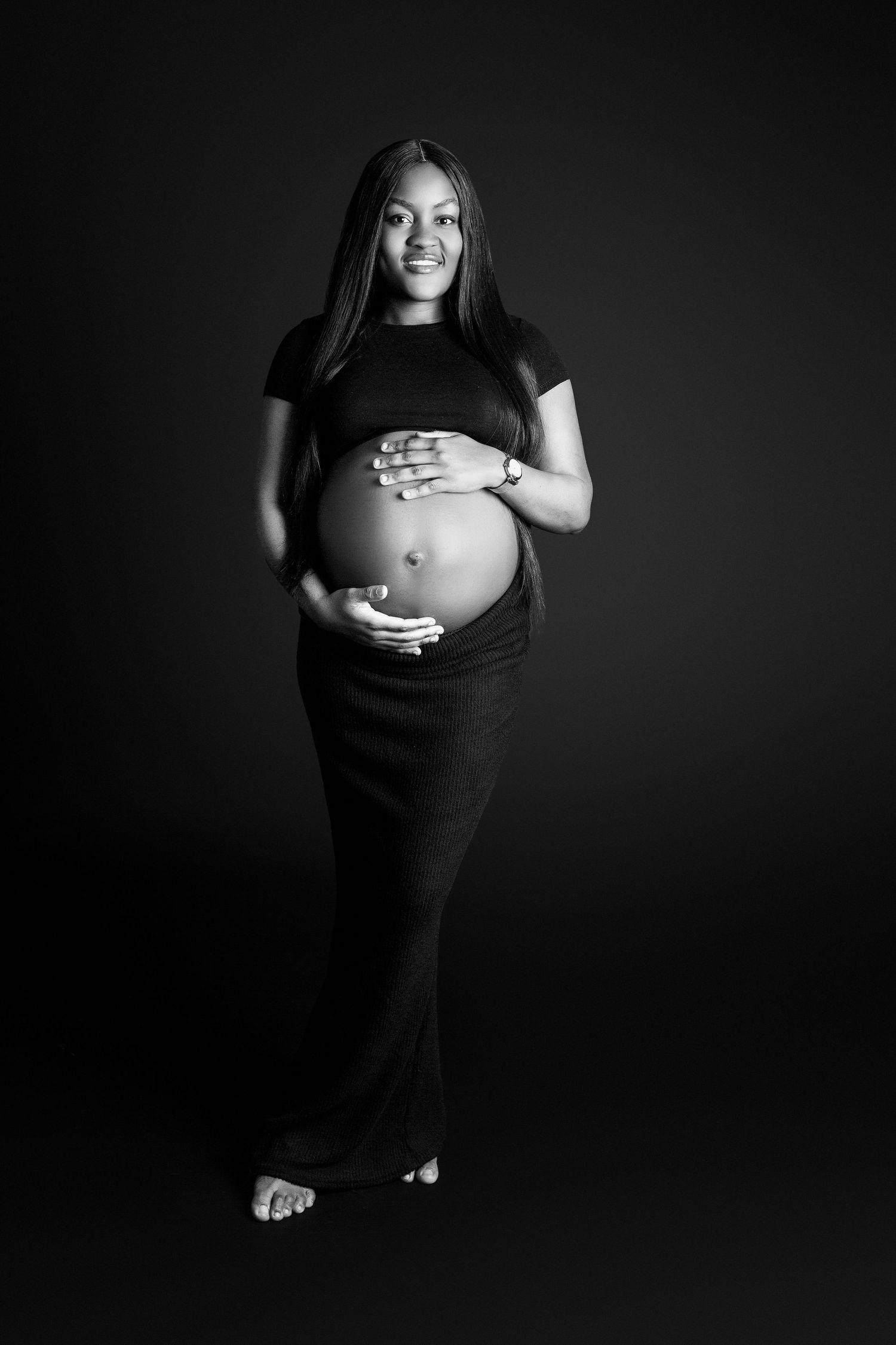 A beautiful full maternity portrait of mum, hands gently placed in a yin yang style around the bump.