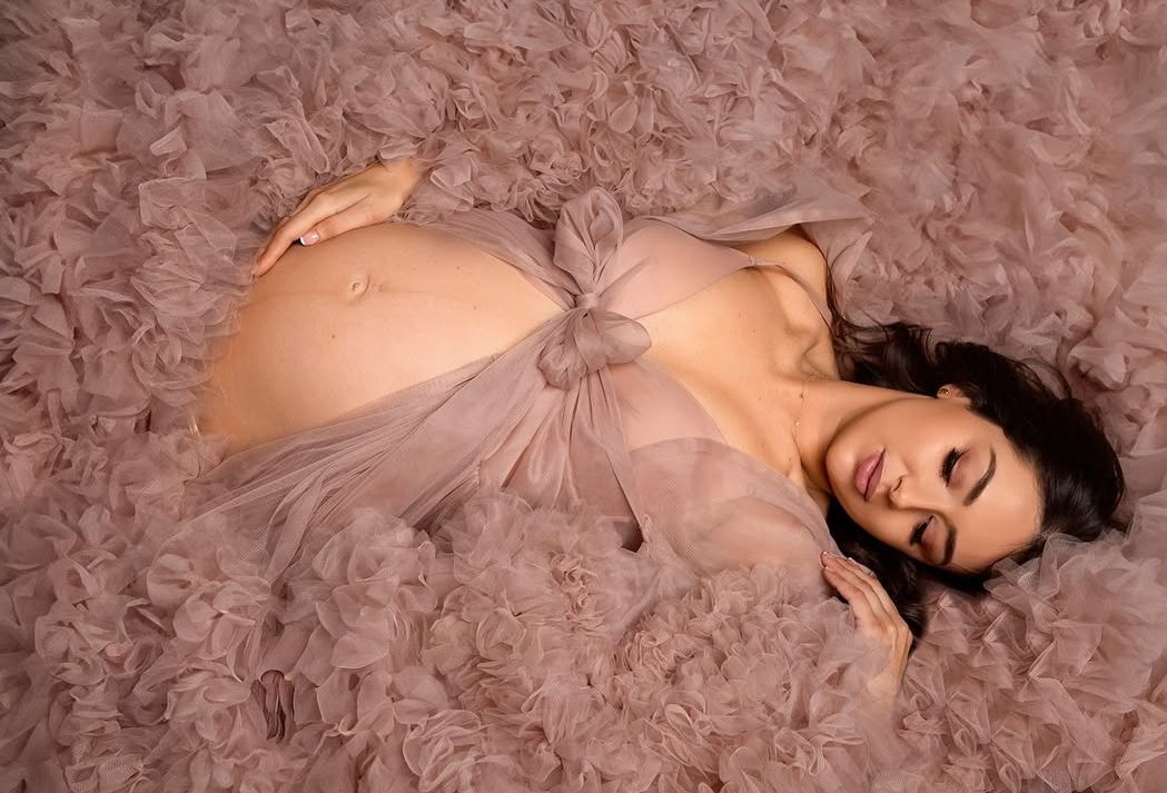 A breathtaking maternity portrait featuring soft, flowing pink fabric, elegantly draped to celebrate the bump.