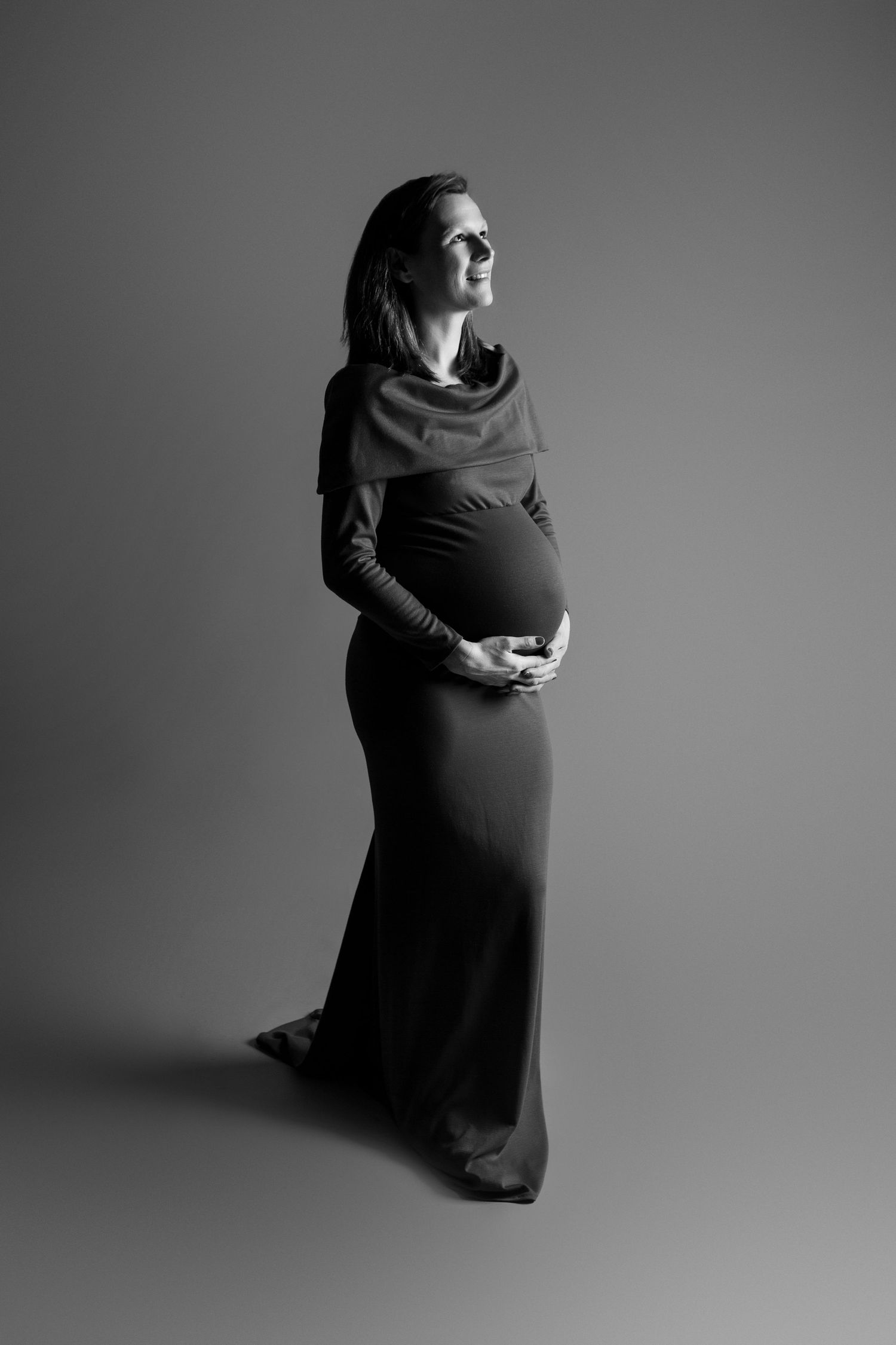 A striking black and white maternity portrait of mum standing alone, celebrating strength and natural beauty.