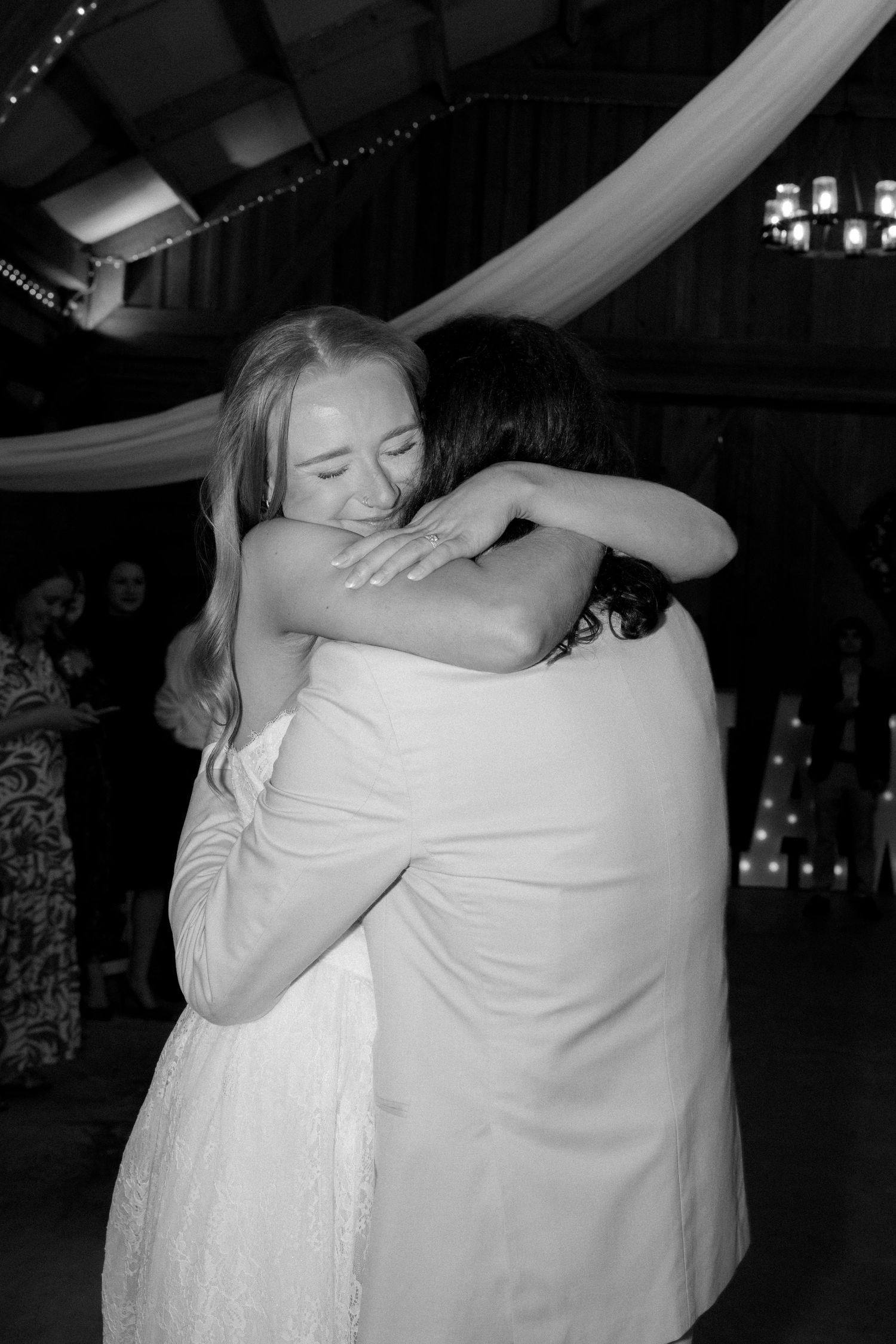 Bride and guest share an emotional hug on the dance floor at a rustic barn wedding reception.