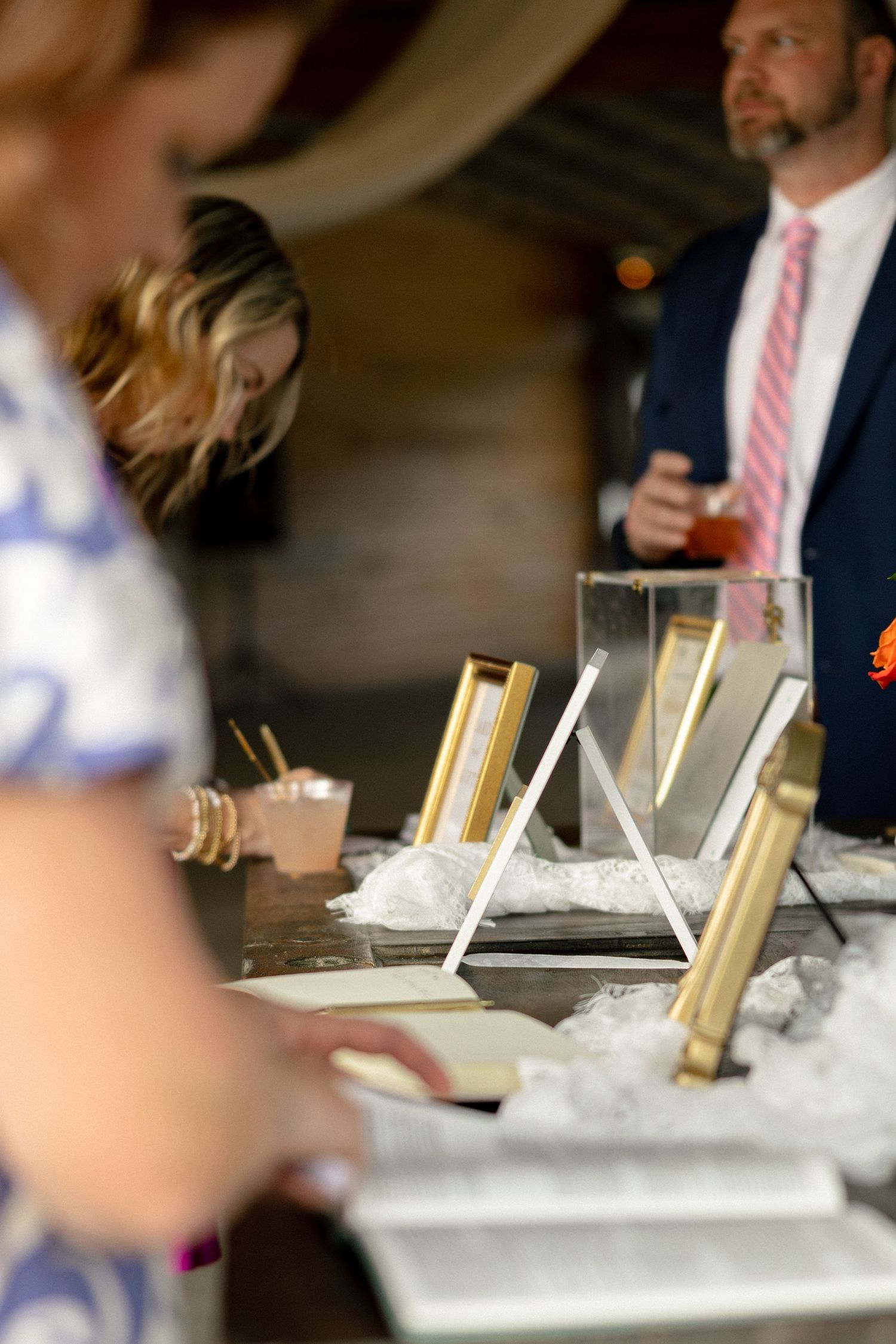 Wedding bar setup with gold-framed drink menus displayed on ice at an indoor reception.