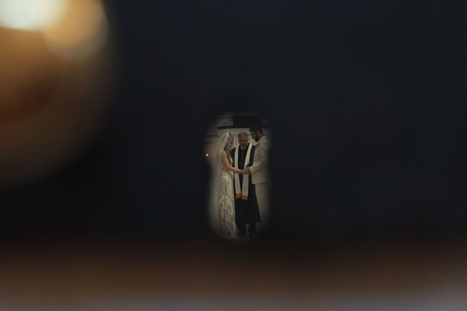 A mysterious keyhole view reveals a dimly lit figure standing in an ancient doorway with warm golden light.
