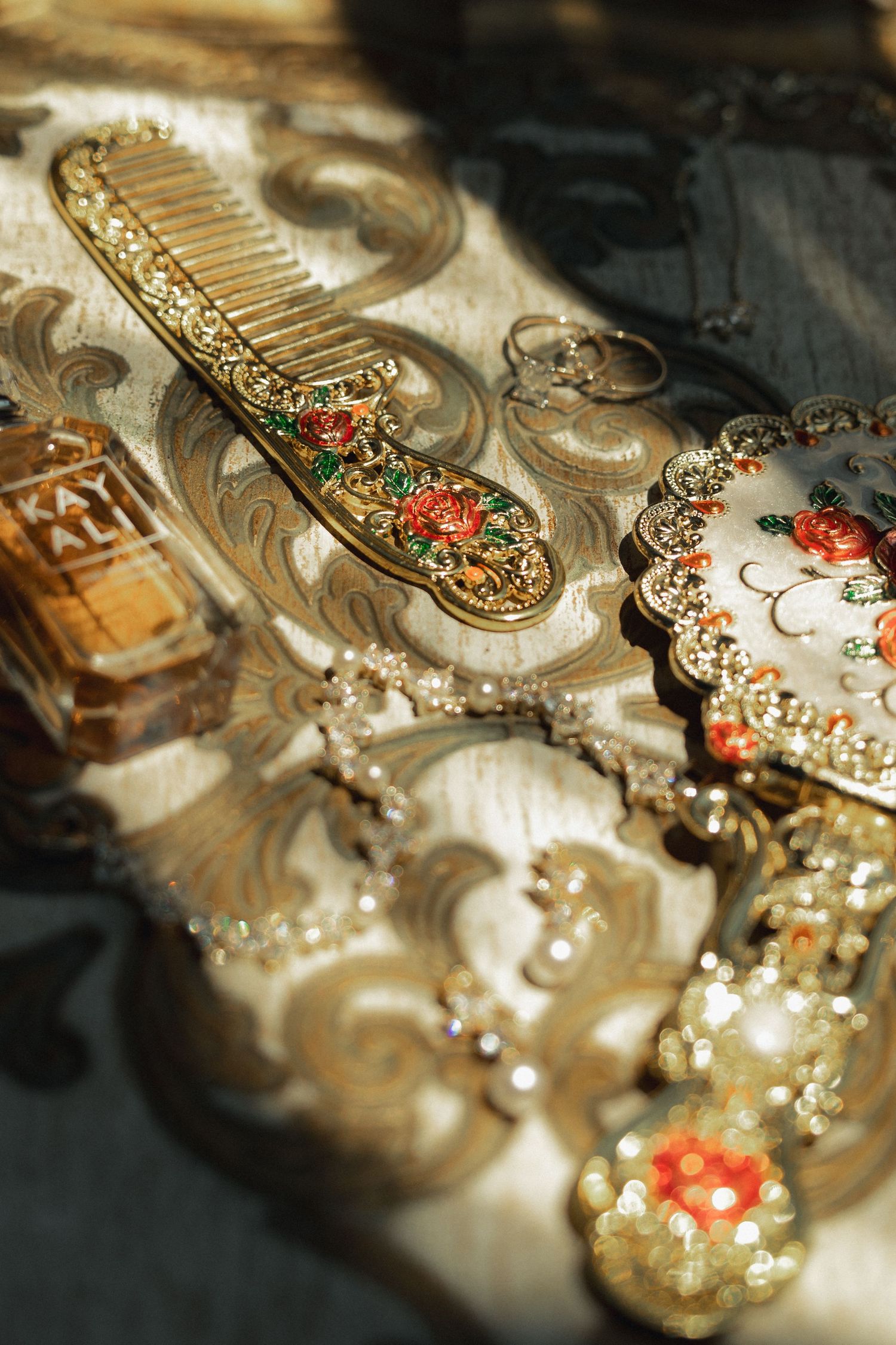 Ornate vintage gold vanity set with jeweled hair comb, hand mirror, and perfume bottle on decorative tray.