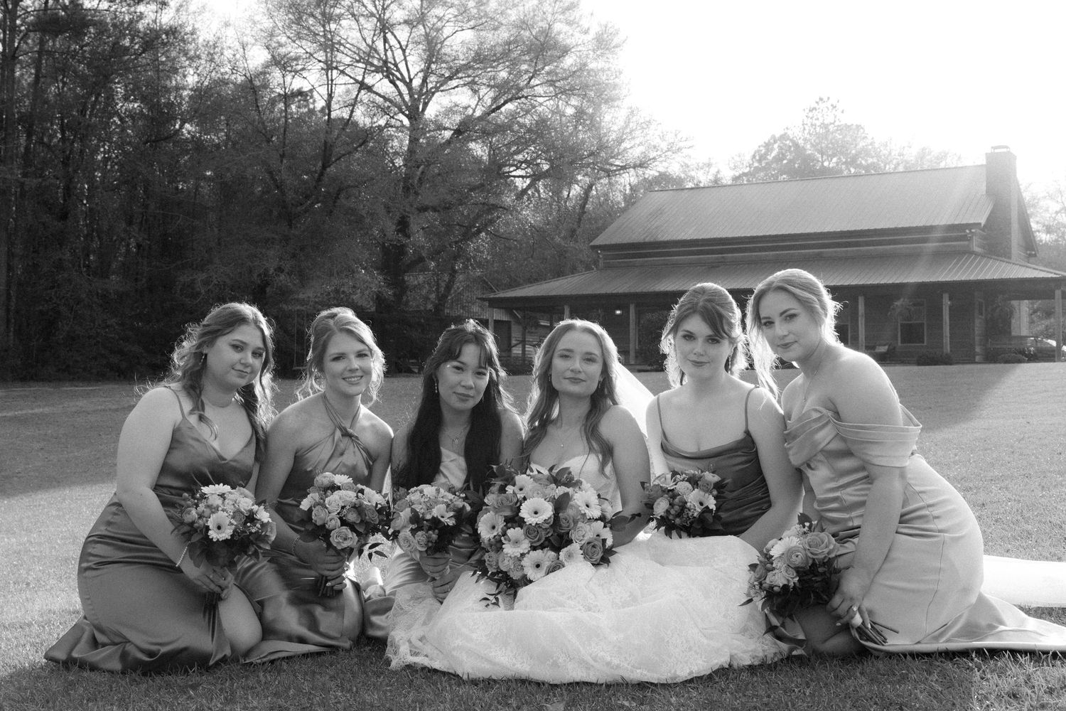 Black and white photo of bride and six bridesmaids posing together with bouquets on wedding day.