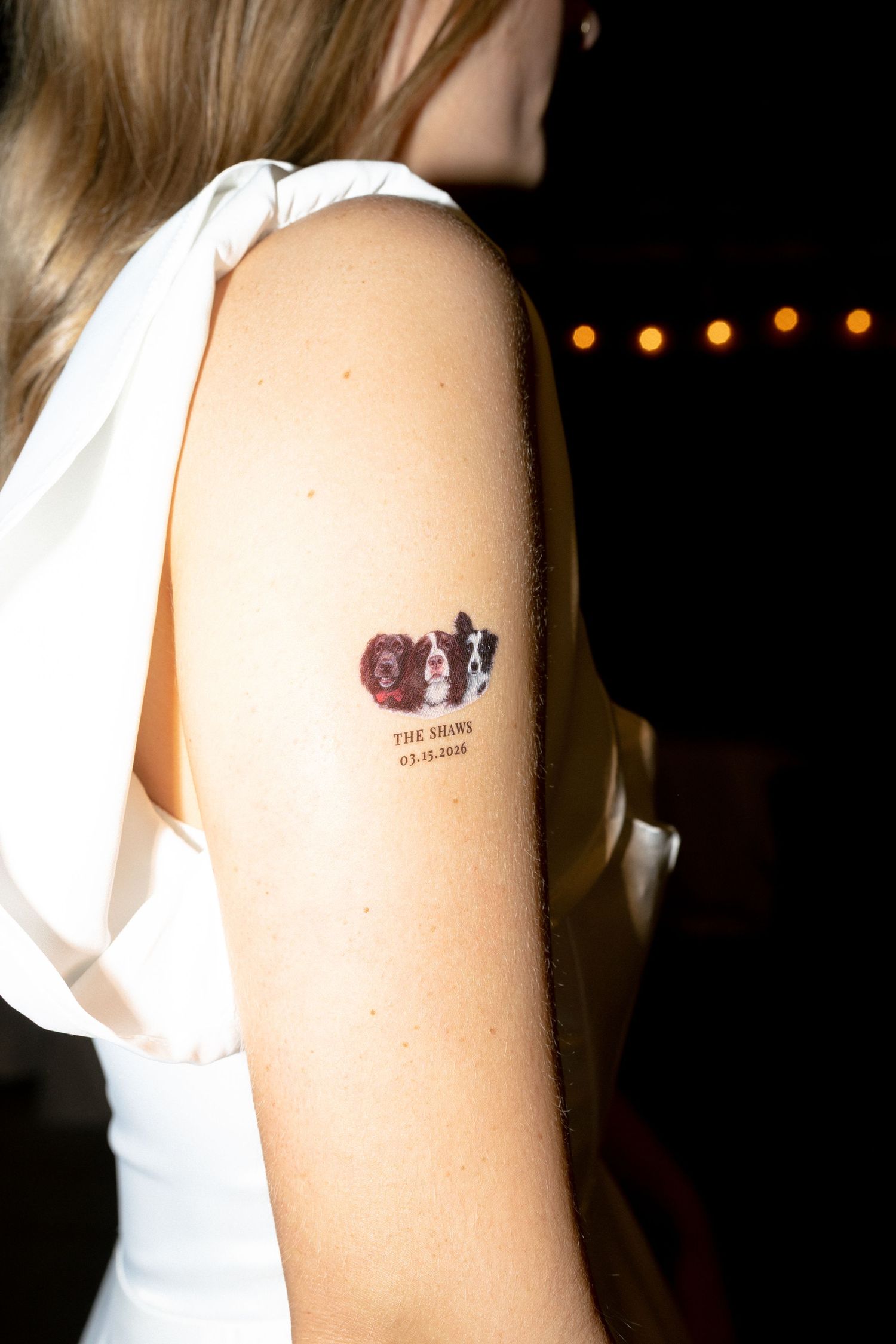 Close-up of a wedding date temporary tattoo featuring a dog on the bride's shoulder at reception.