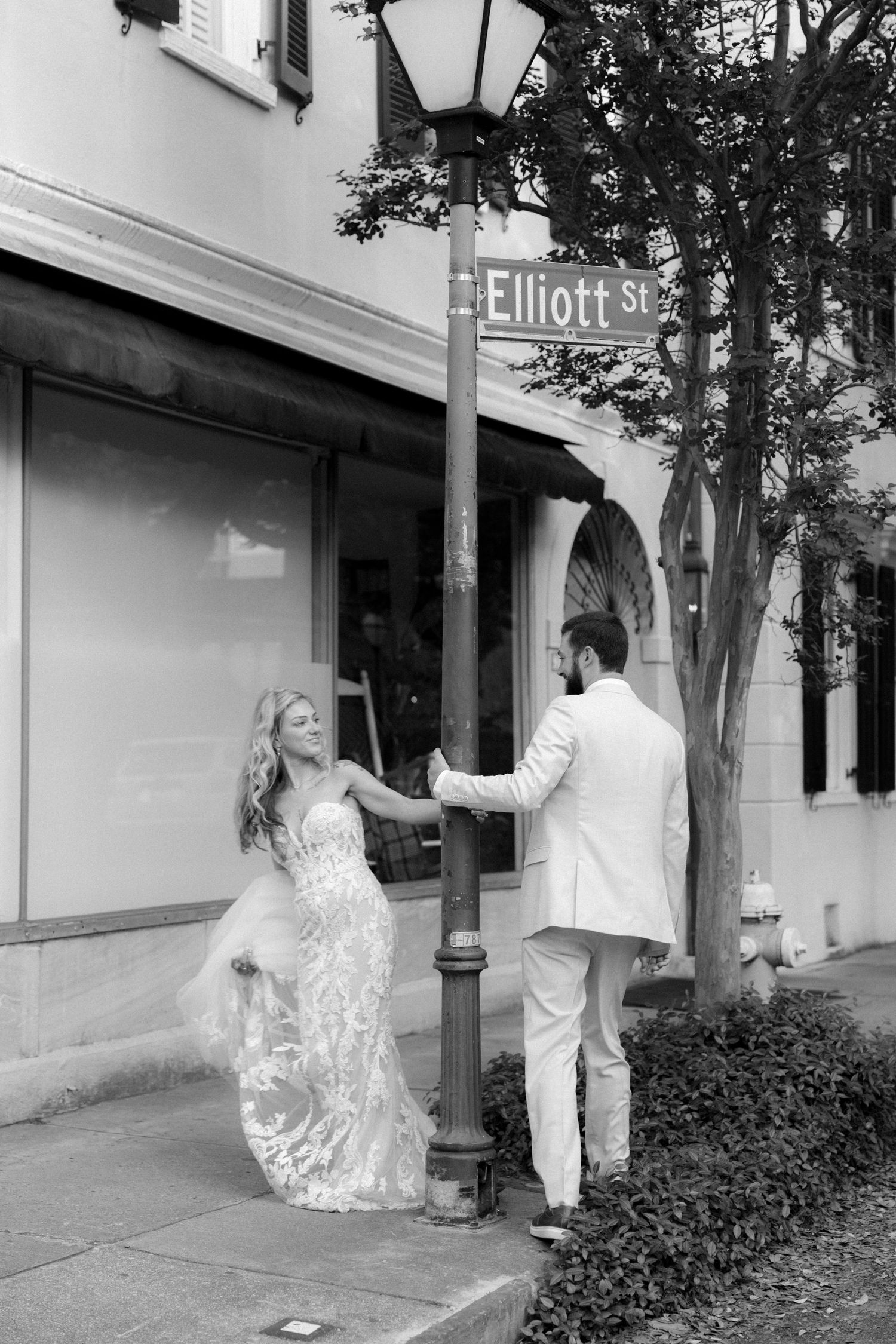 Black and white photo of a bride and groom sharing a romantic moment by an Elliott St street sign.