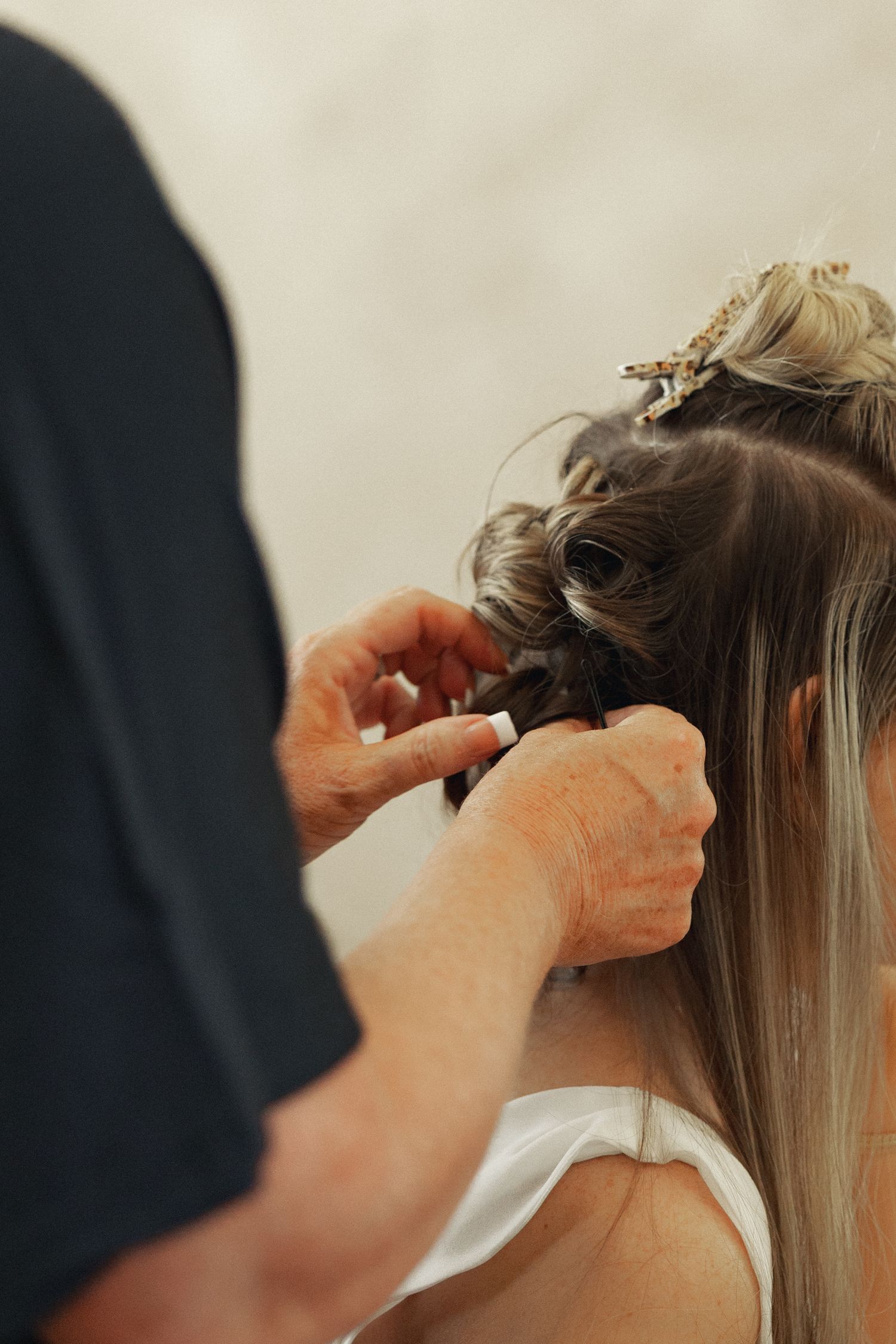 A hairstylist carefully braids and pins an elegant updo on a woman with long blonde hair for a special occasion.