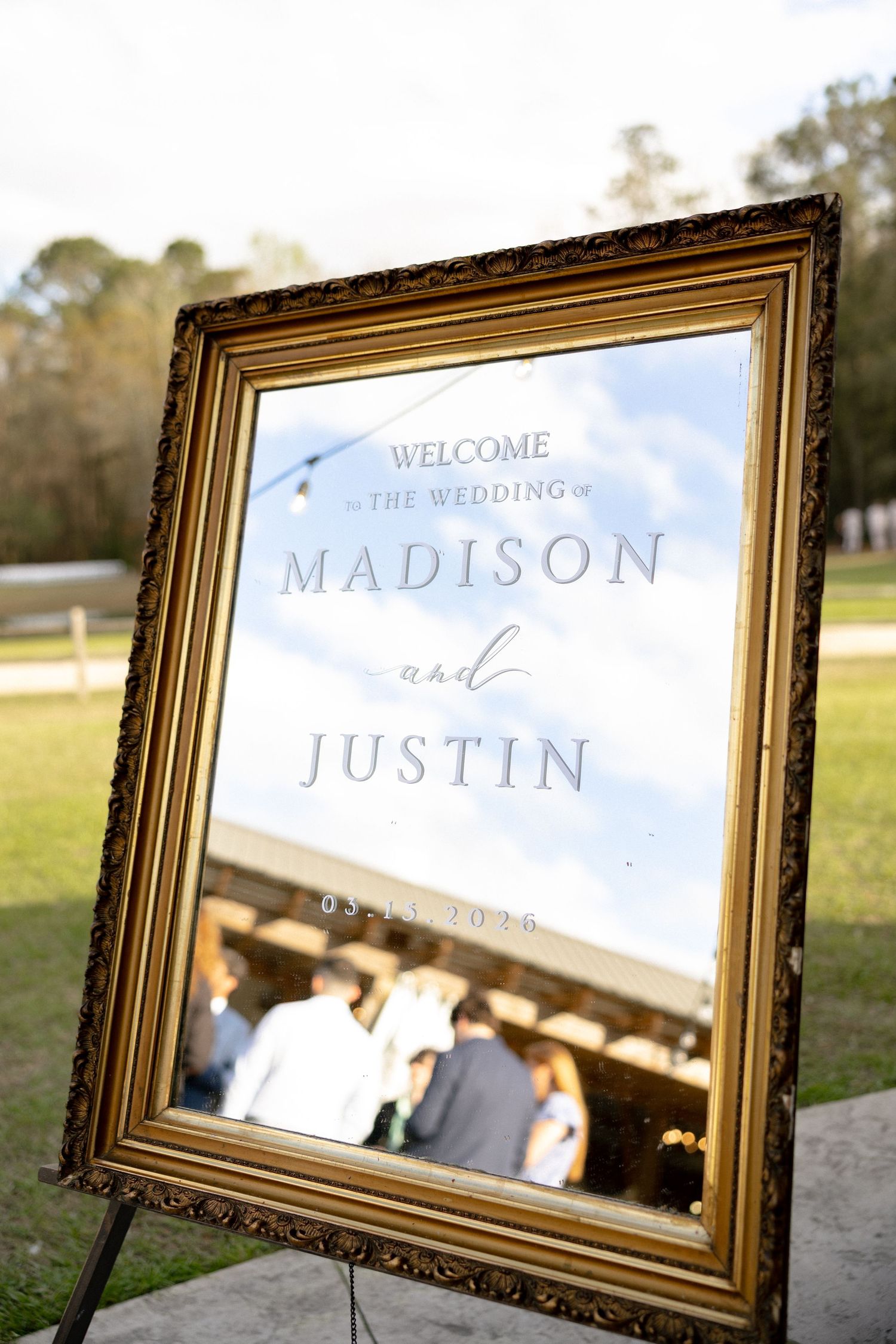 Elegant gold ornate mirror wedding welcome sign for Madison and Justin dated 03-11-2025 outdoors.