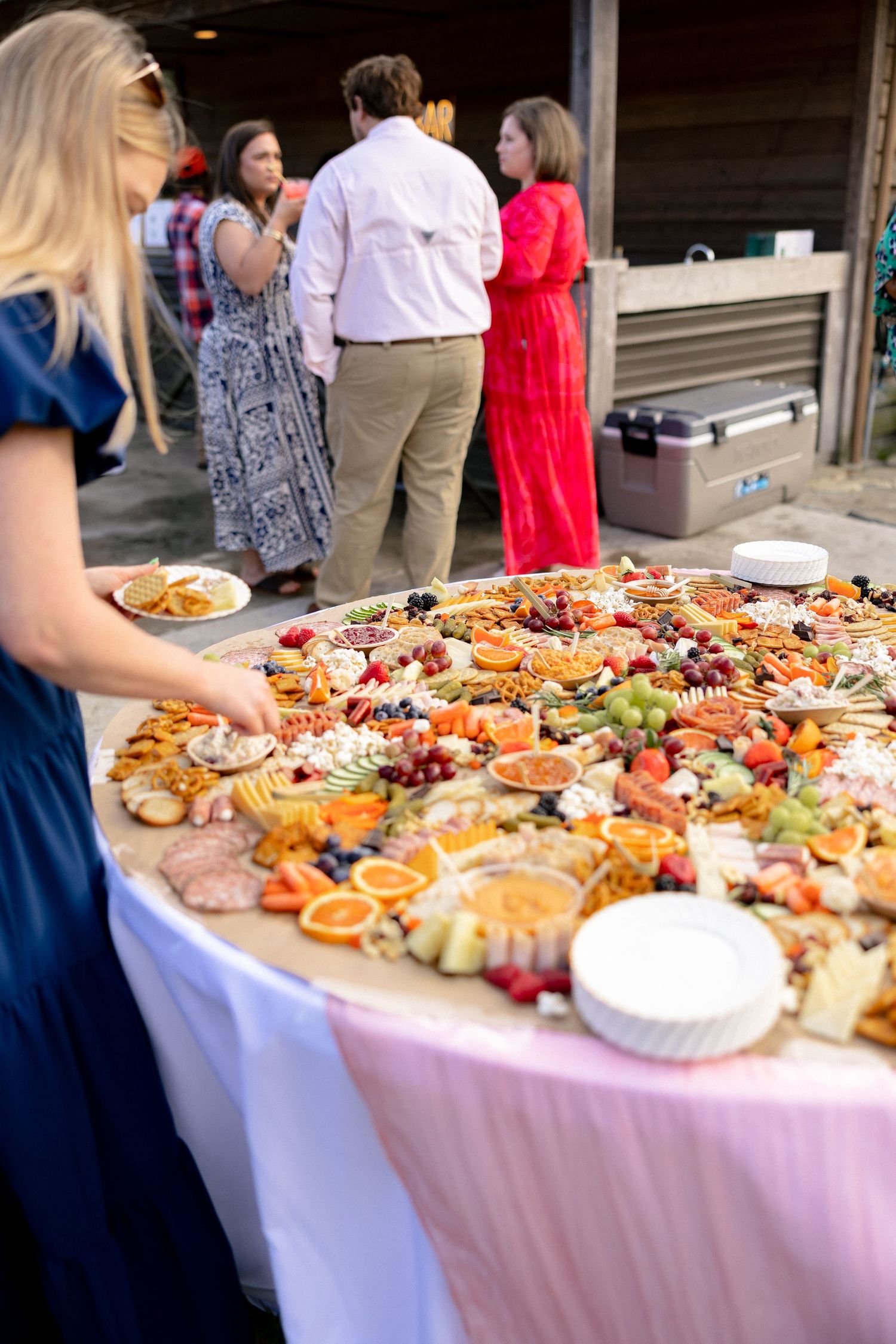 Elegant wedding charcuterie grazing table with fruits, cheeses, and meats at an outdoor reception.