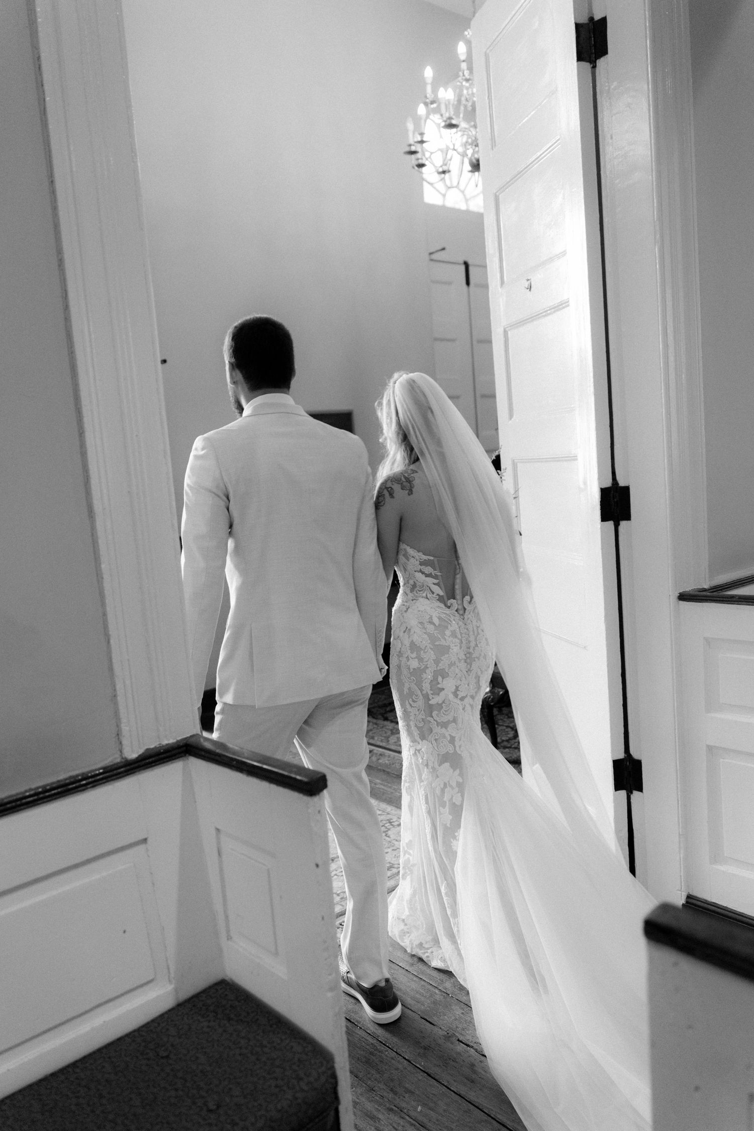 Black and white photo of bride and groom walking up stairs after their church wedding ceremony.